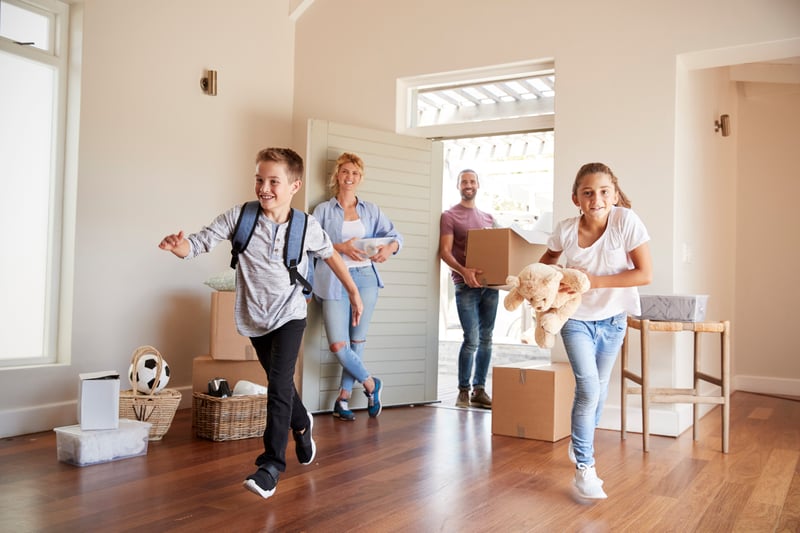 A family smiles while moving into a house.