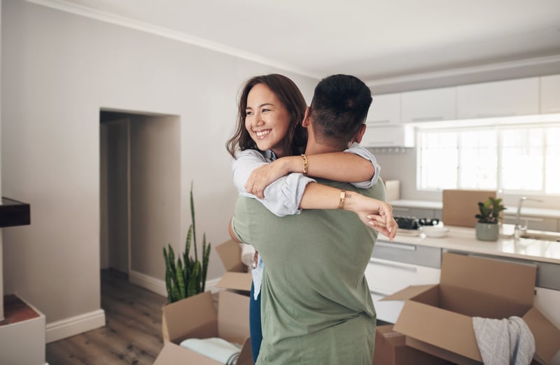 A man and woman hug after moving into a new house.