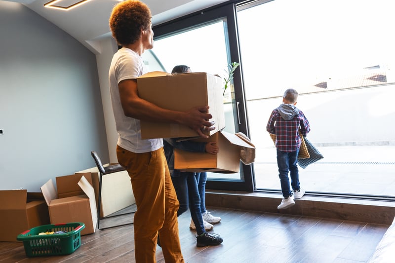 People carry boxes into a new house.