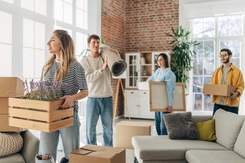 A family carries furniture into a new house.
