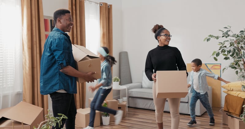 A couple smiles while moving boxes into a new house.