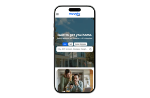Smartphone screen displaying the Movoto by Lower homepage with the headline “Built to get you home,” a search bar for city or address, and options to buy, sell, or view home estimates, with an image of a couple looking at a phone below.