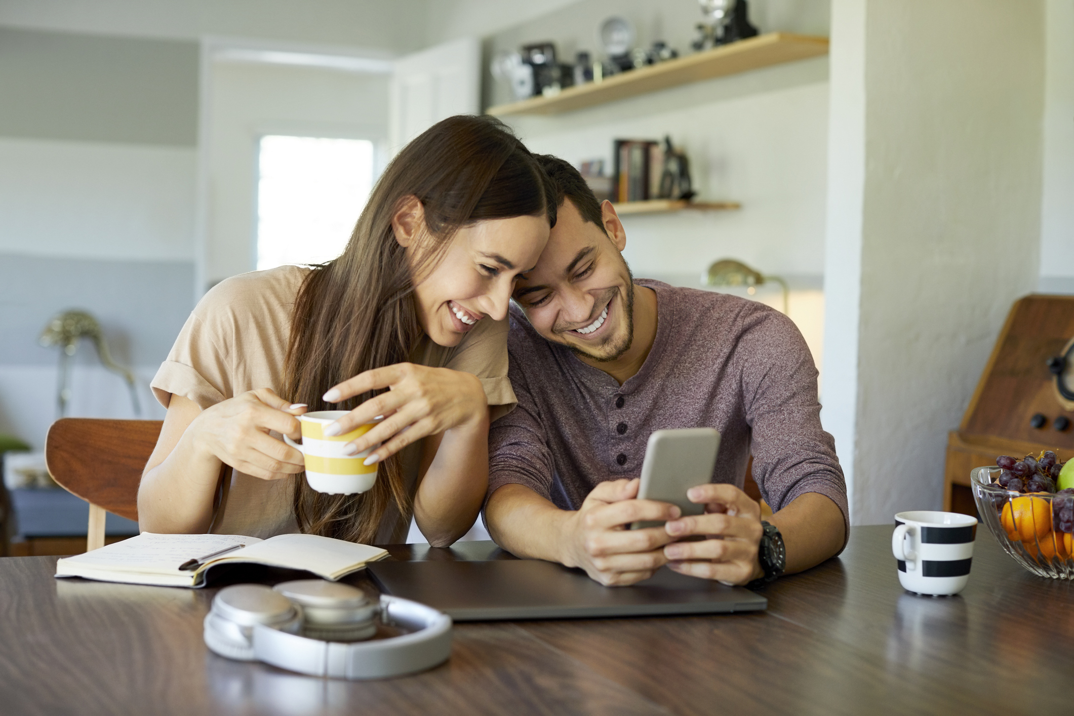 A man and a woman smiling and looking at a phone.
