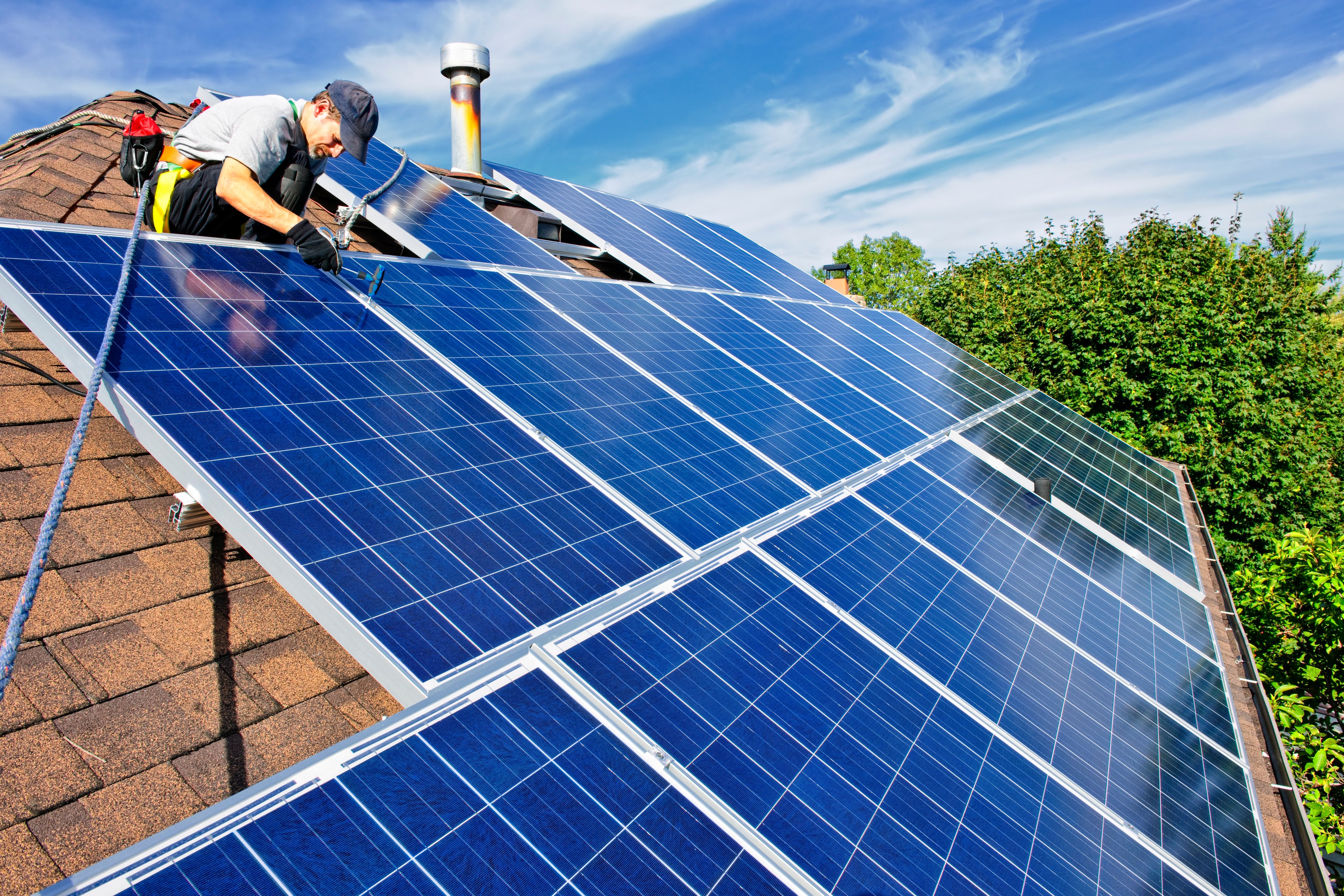A technician installs solar panels on a single-family home's roof.