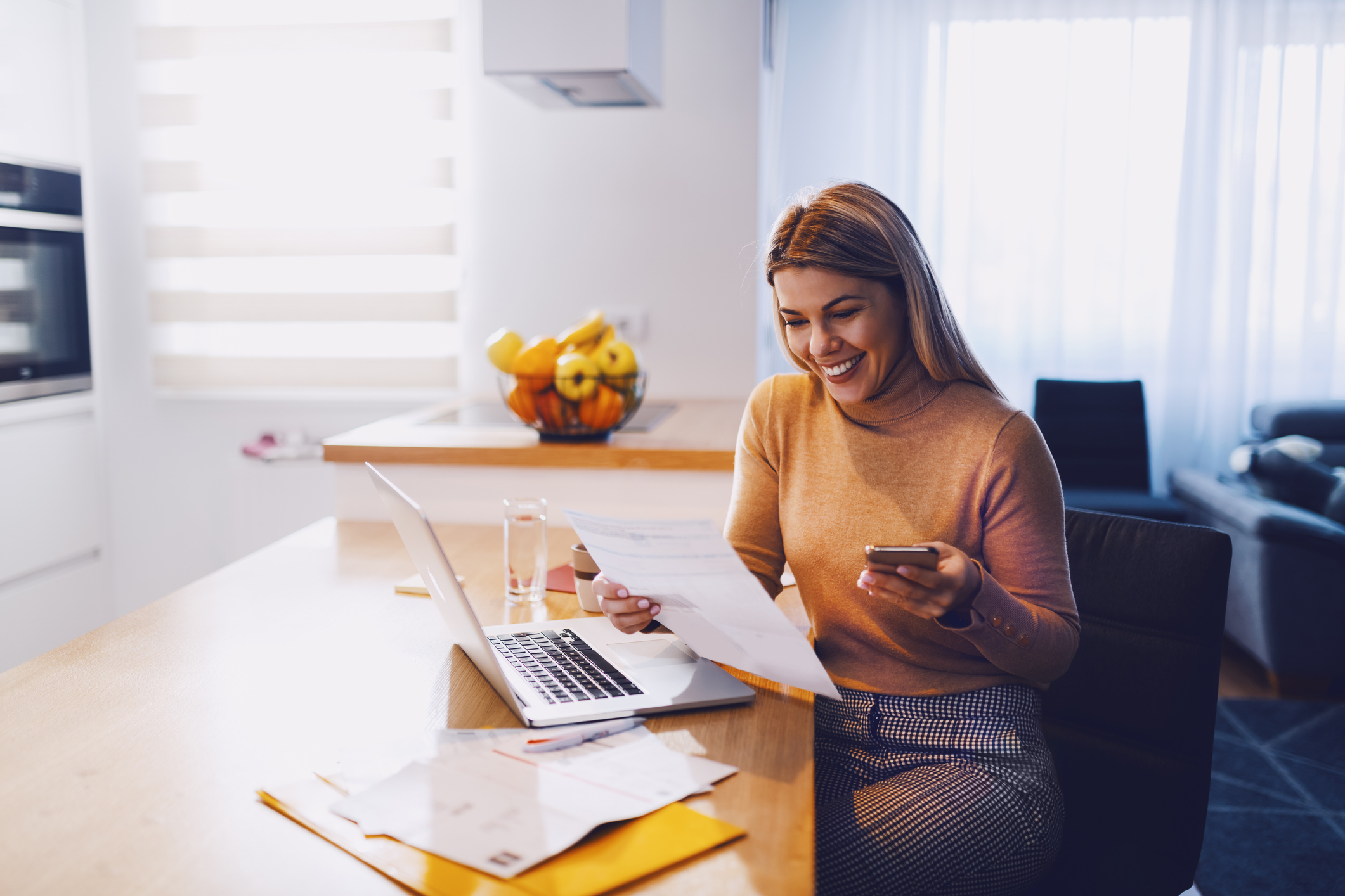 A woman smiles at a laptop.