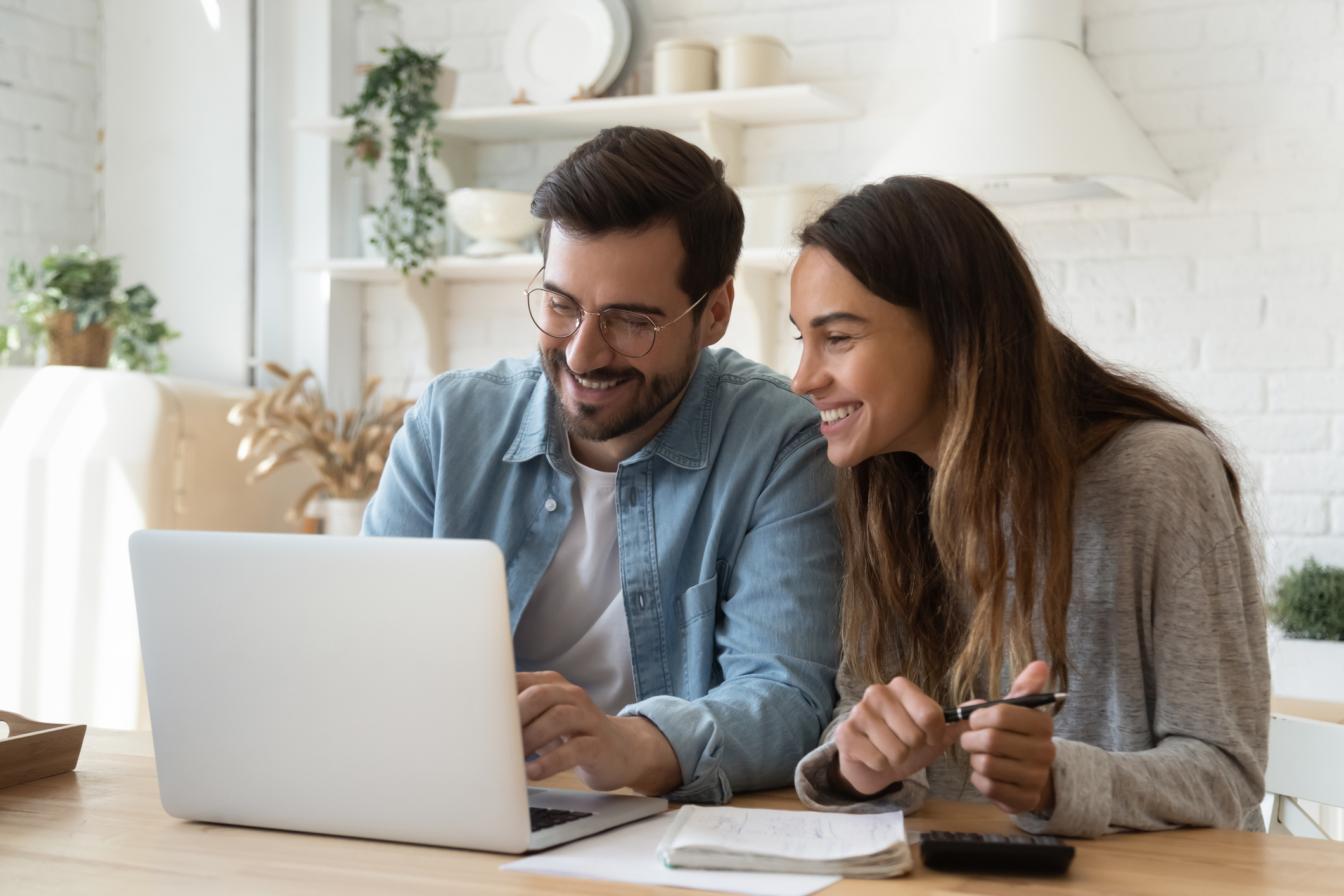 A man and a woman smiling at a laptop.
