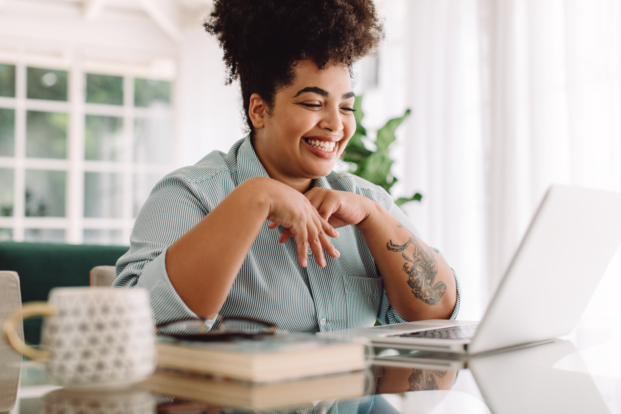 A woman smiles at a laptop while applying for a bank statement loan.