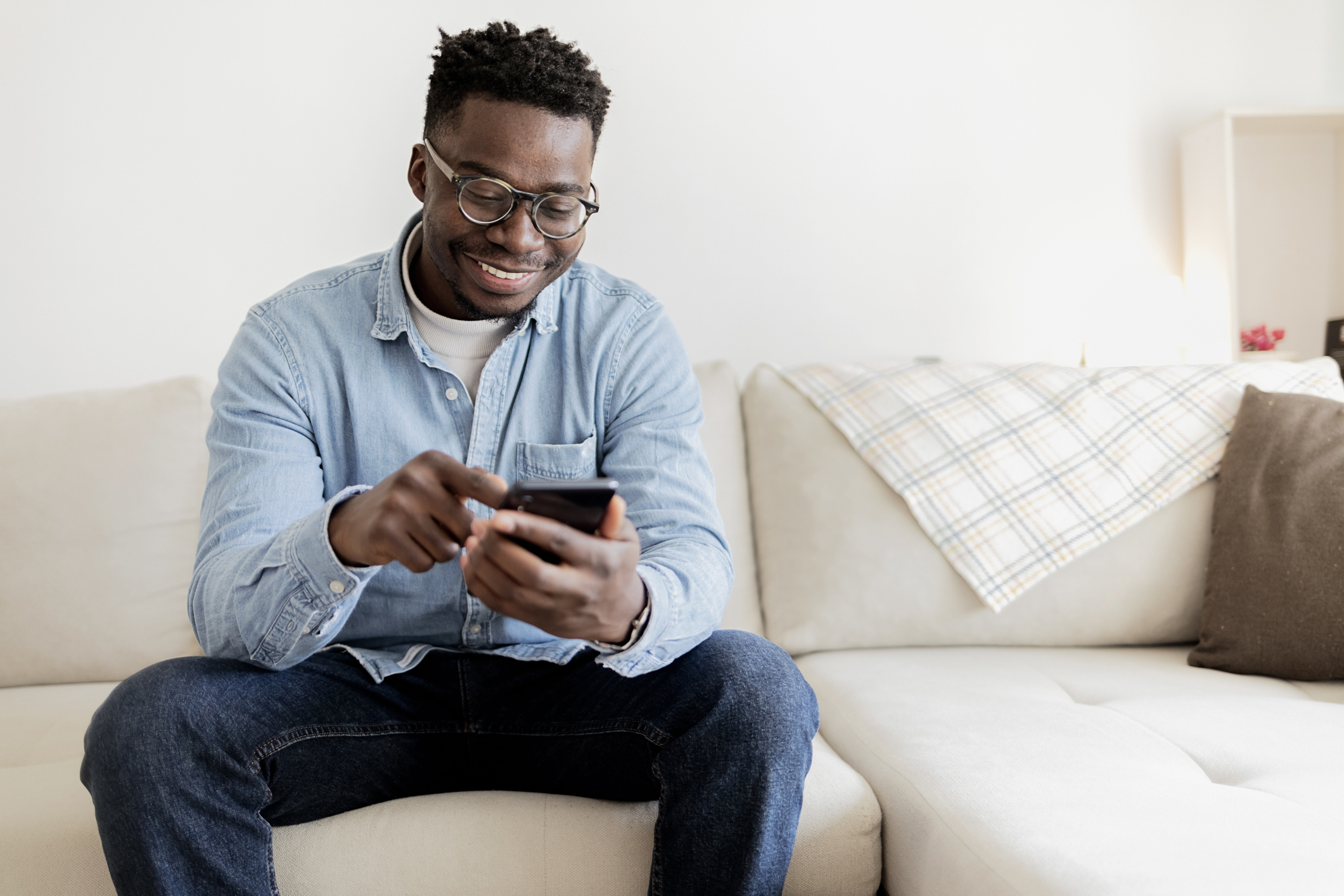 A man smiles at a phone while exploring mortgage options with no W-2 requirement.