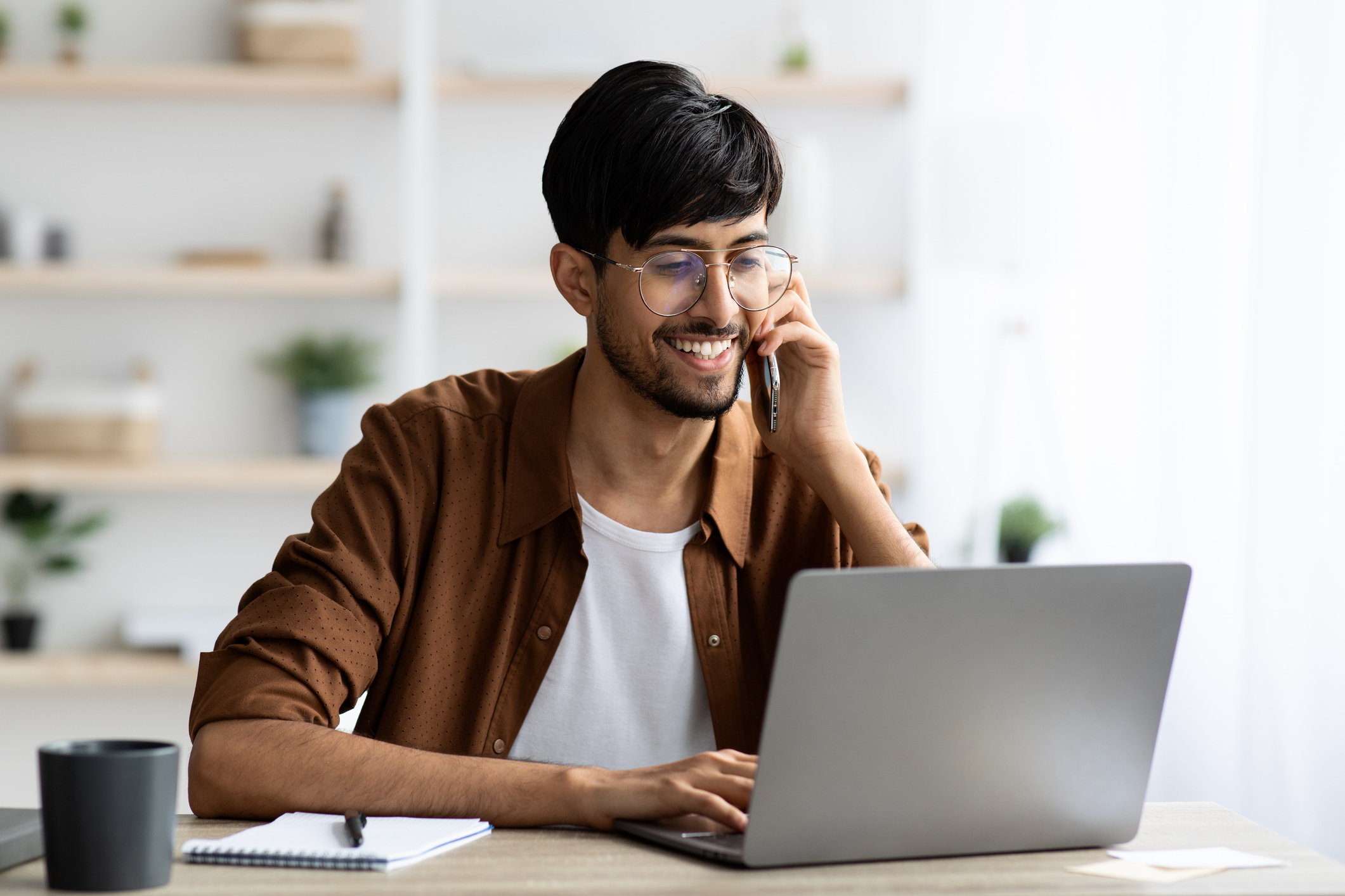 A man smiles at a laptop.
