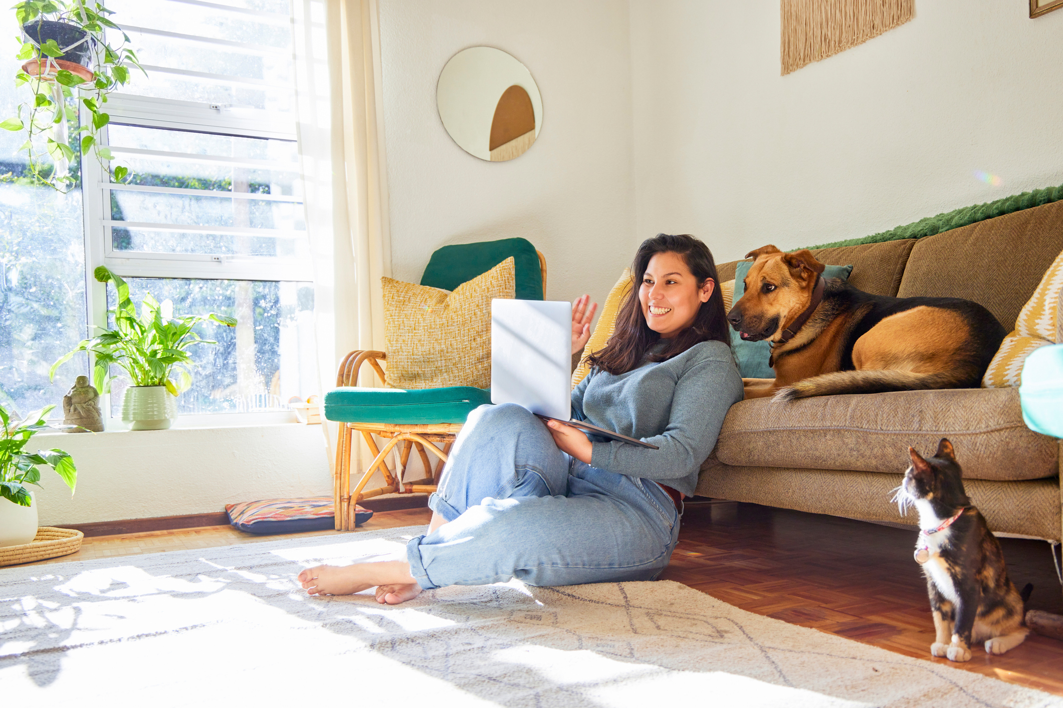 A woman and her dog smile at a laptop.