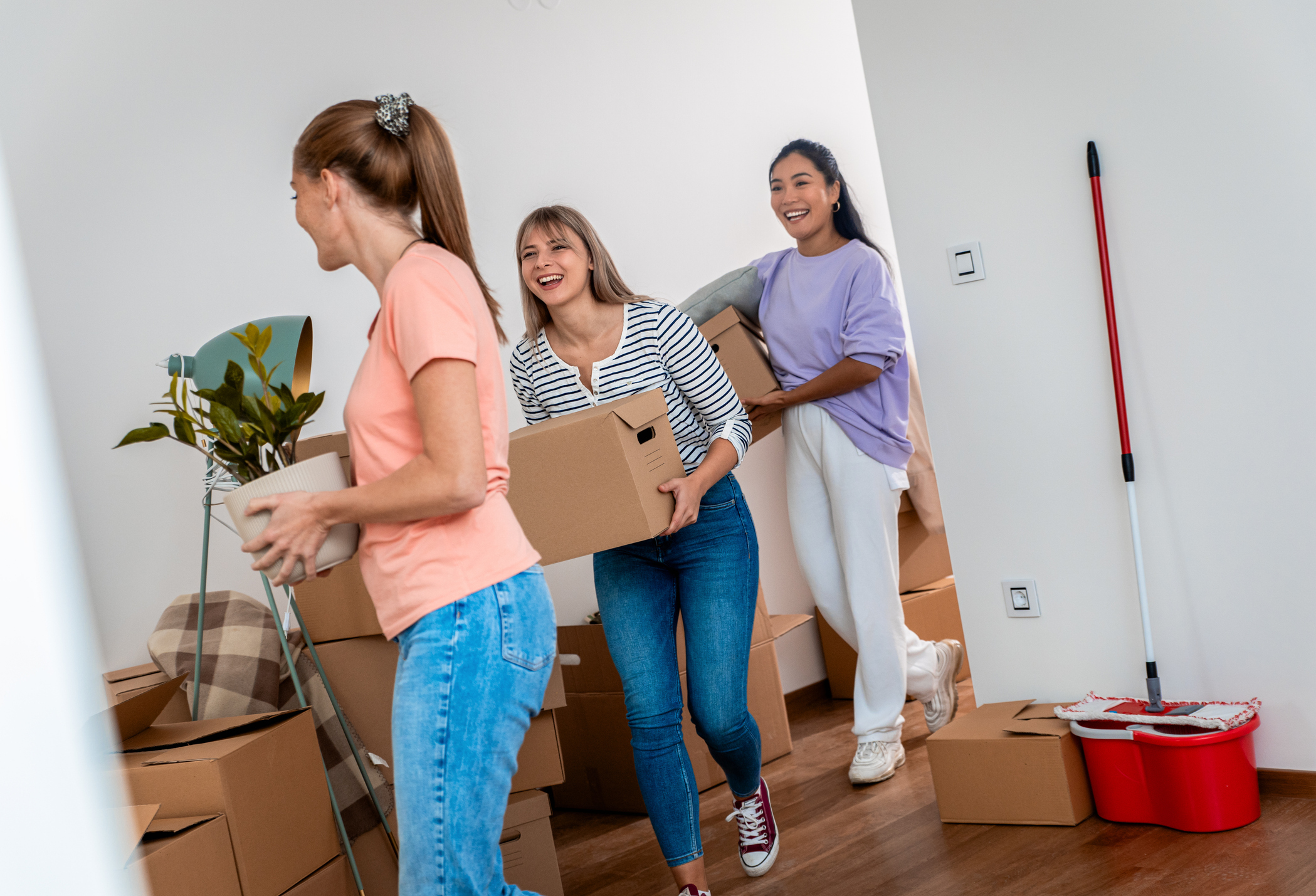 Three women move boxes into a house.