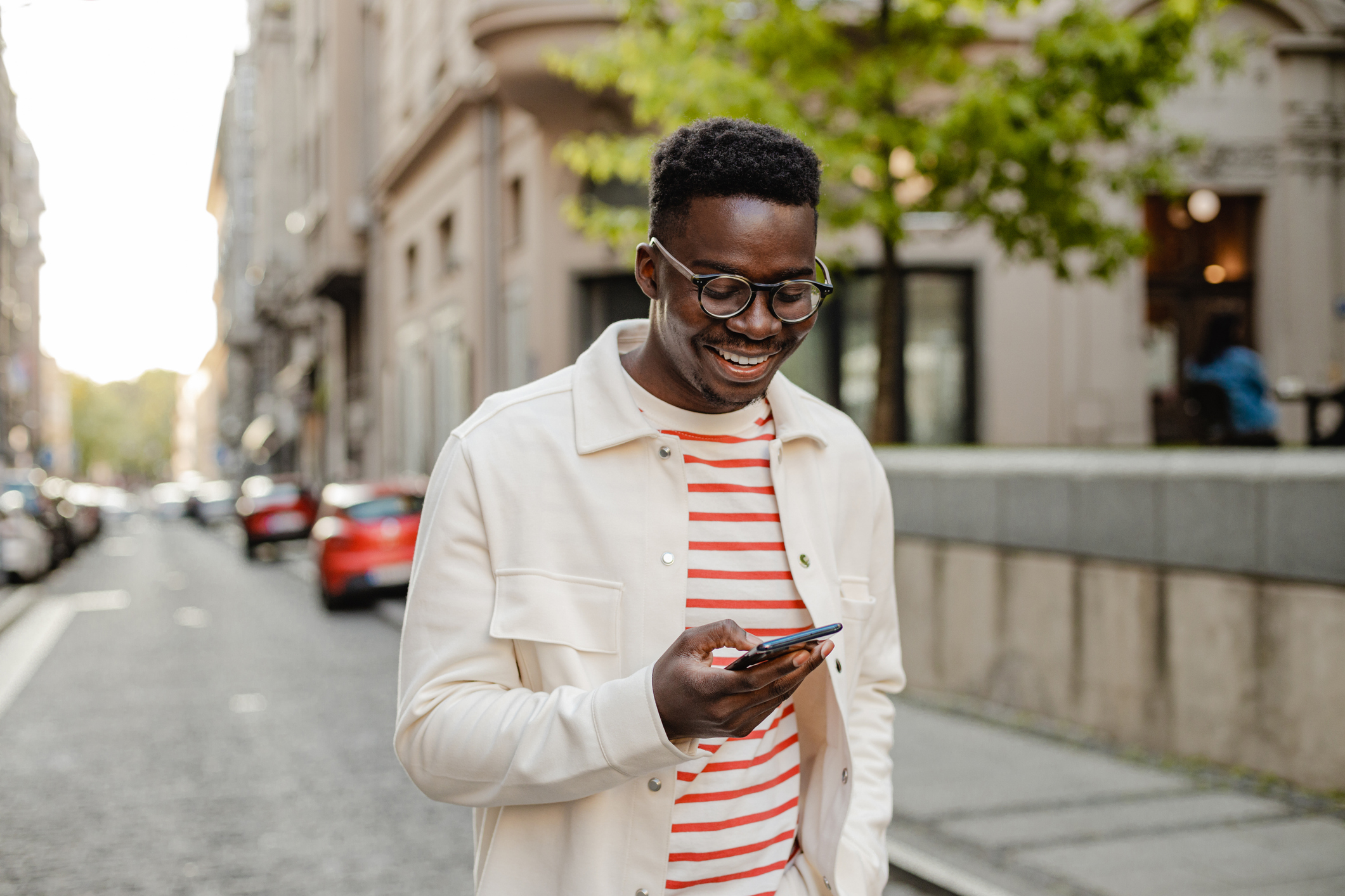 A man smiles while looking at a phone.