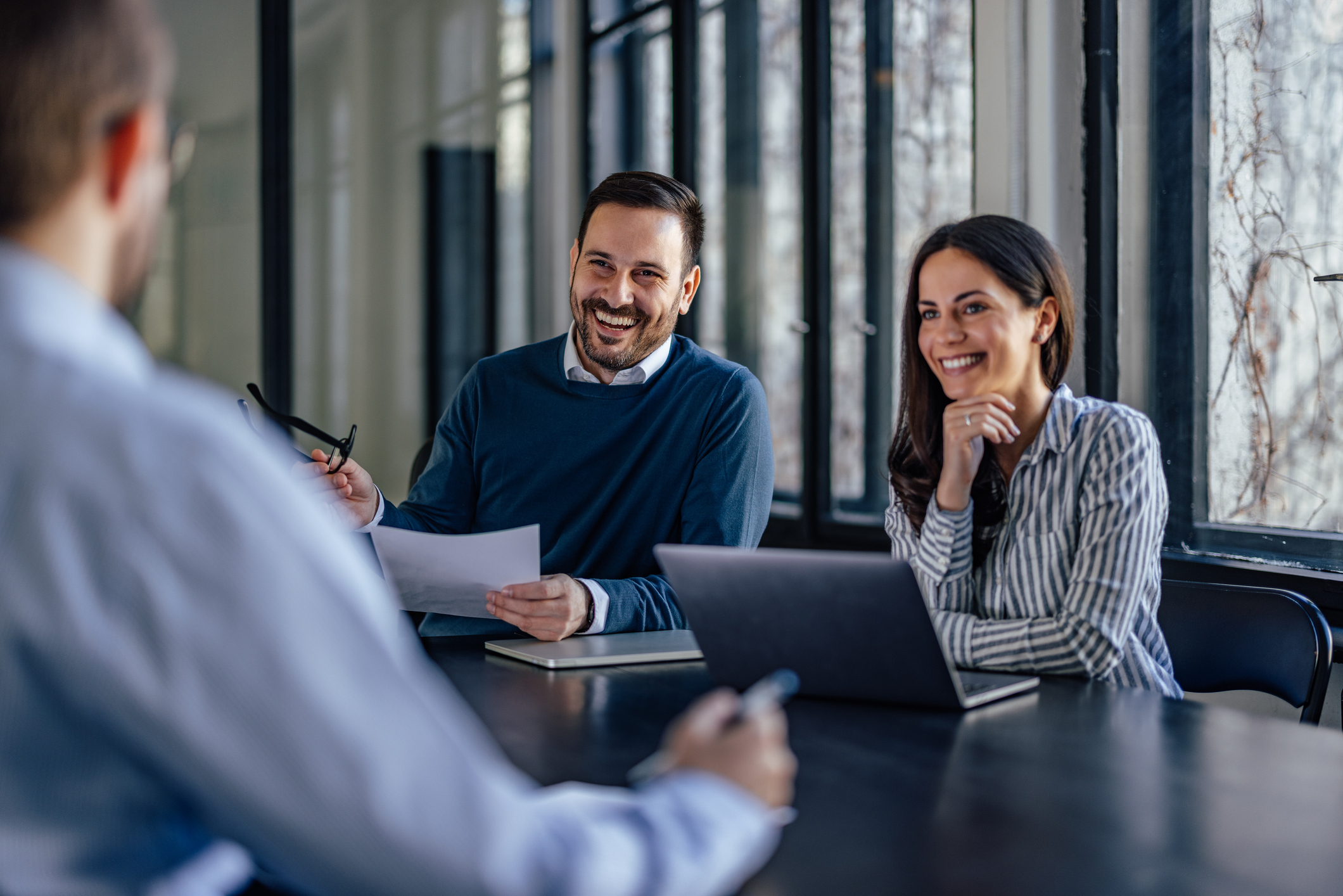 A man and a woman smile while attending a meeting.