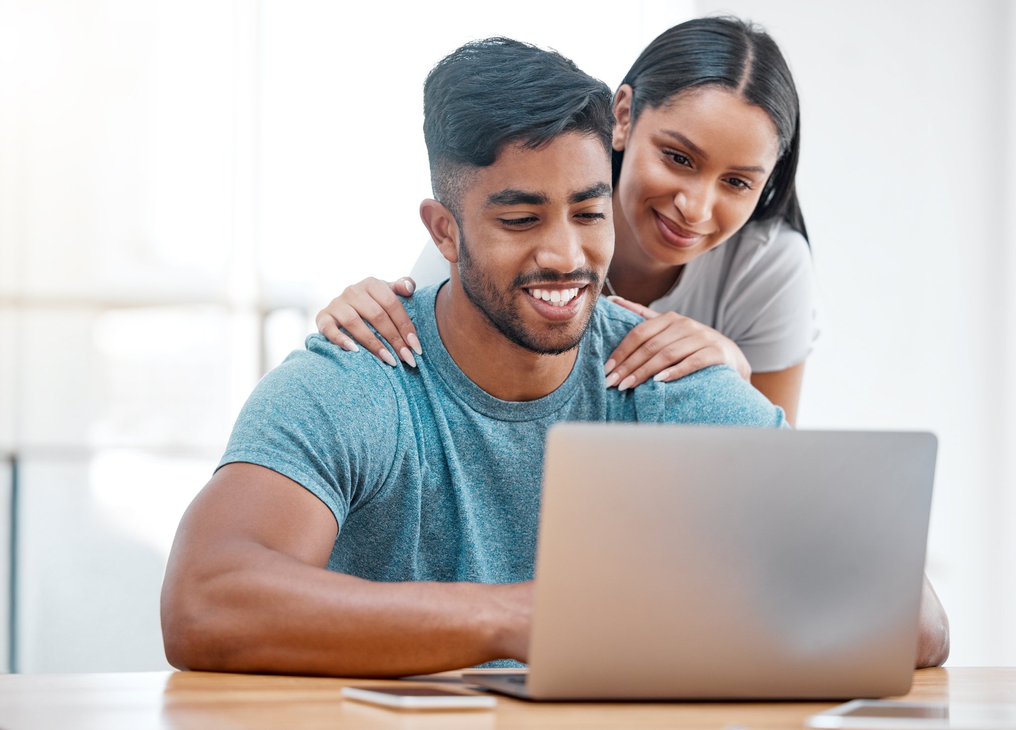 A man and a woman smiling at a laptop.