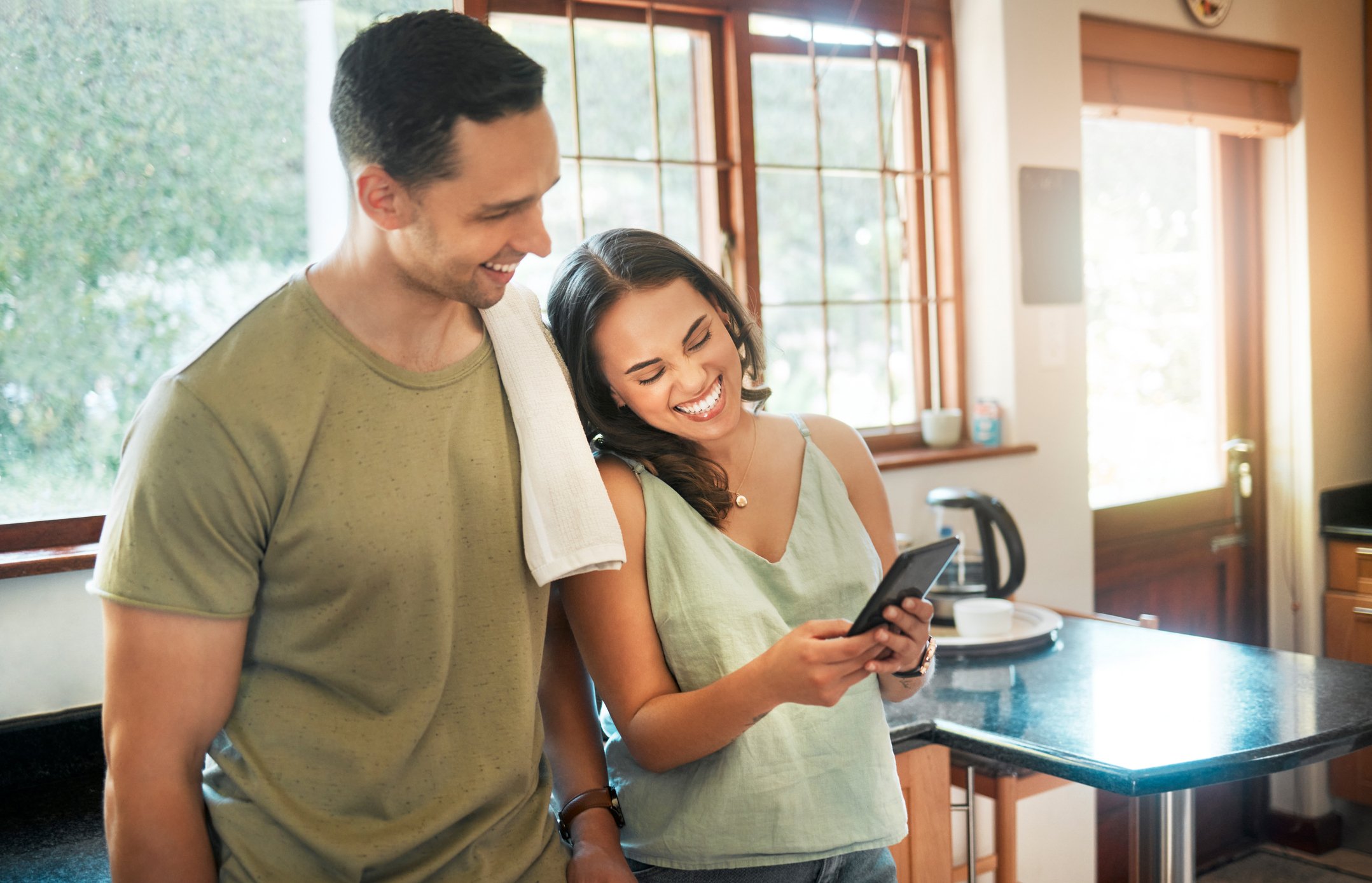 A man and a woman smiling while looking at a phone.