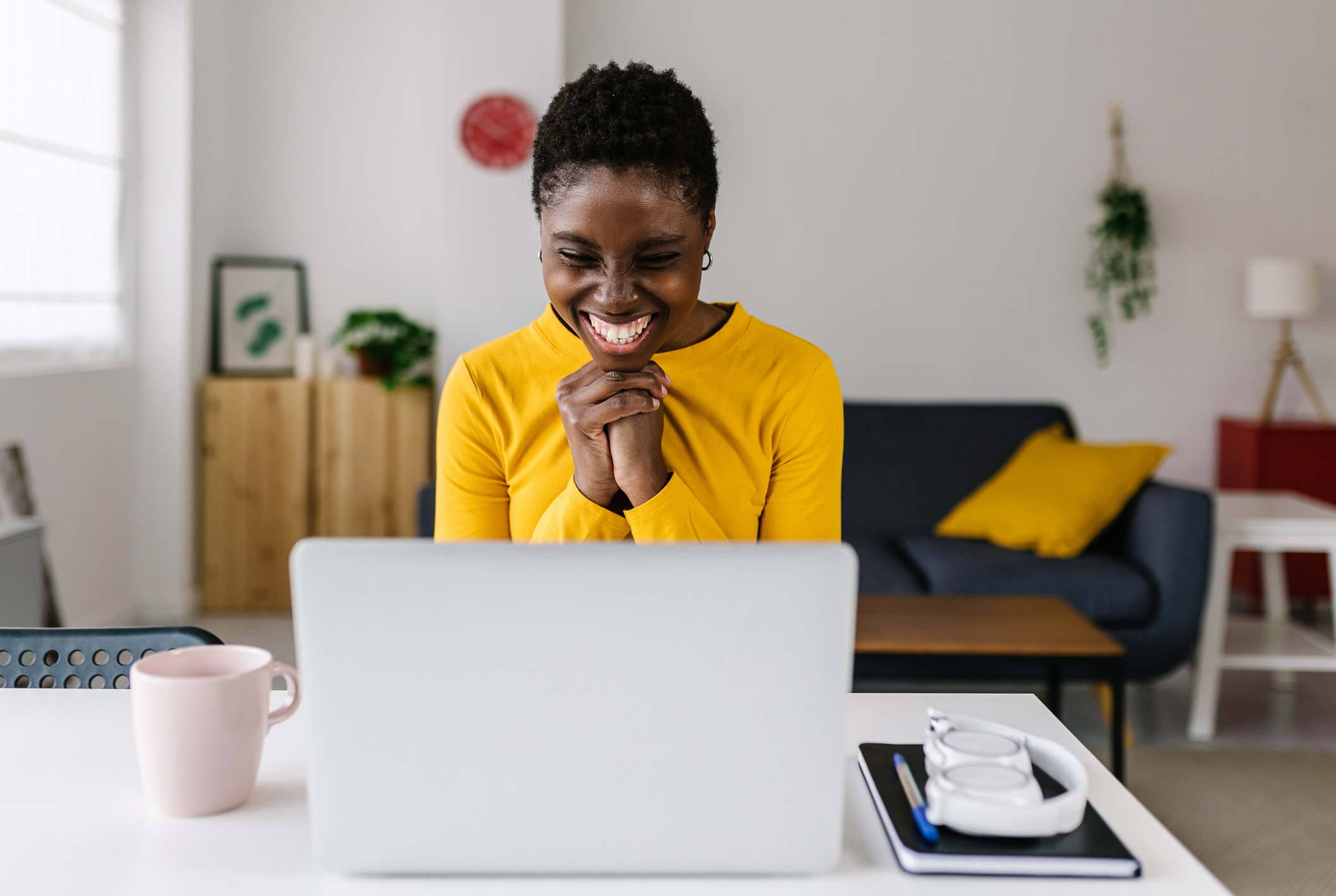 A woman smiles at a laptop while applying for a 1099 loan.