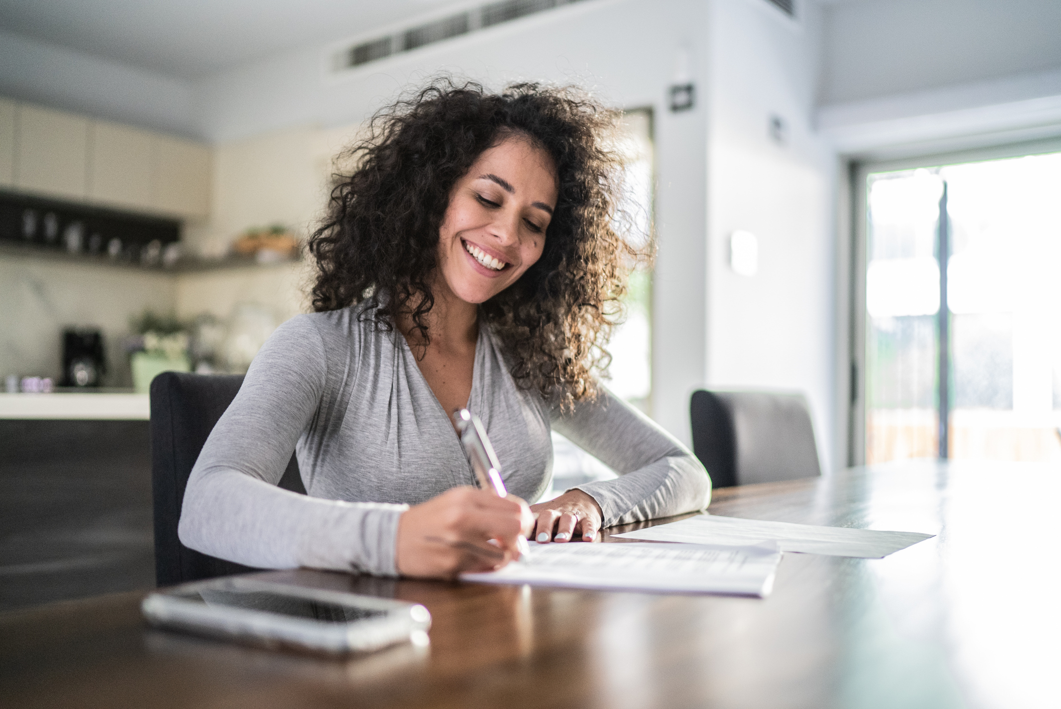 A woman smiles while filling out documents.