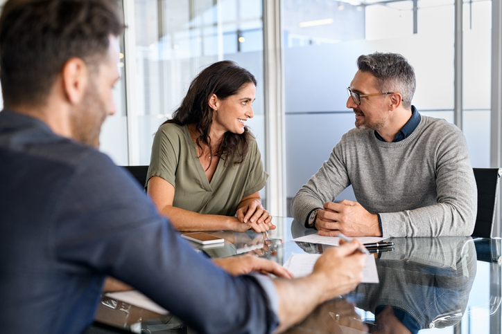 A man and a woman smile while consulting with a salesperson.