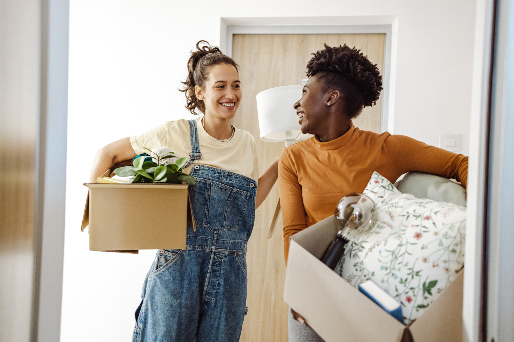 Two women smile while moving boxes.