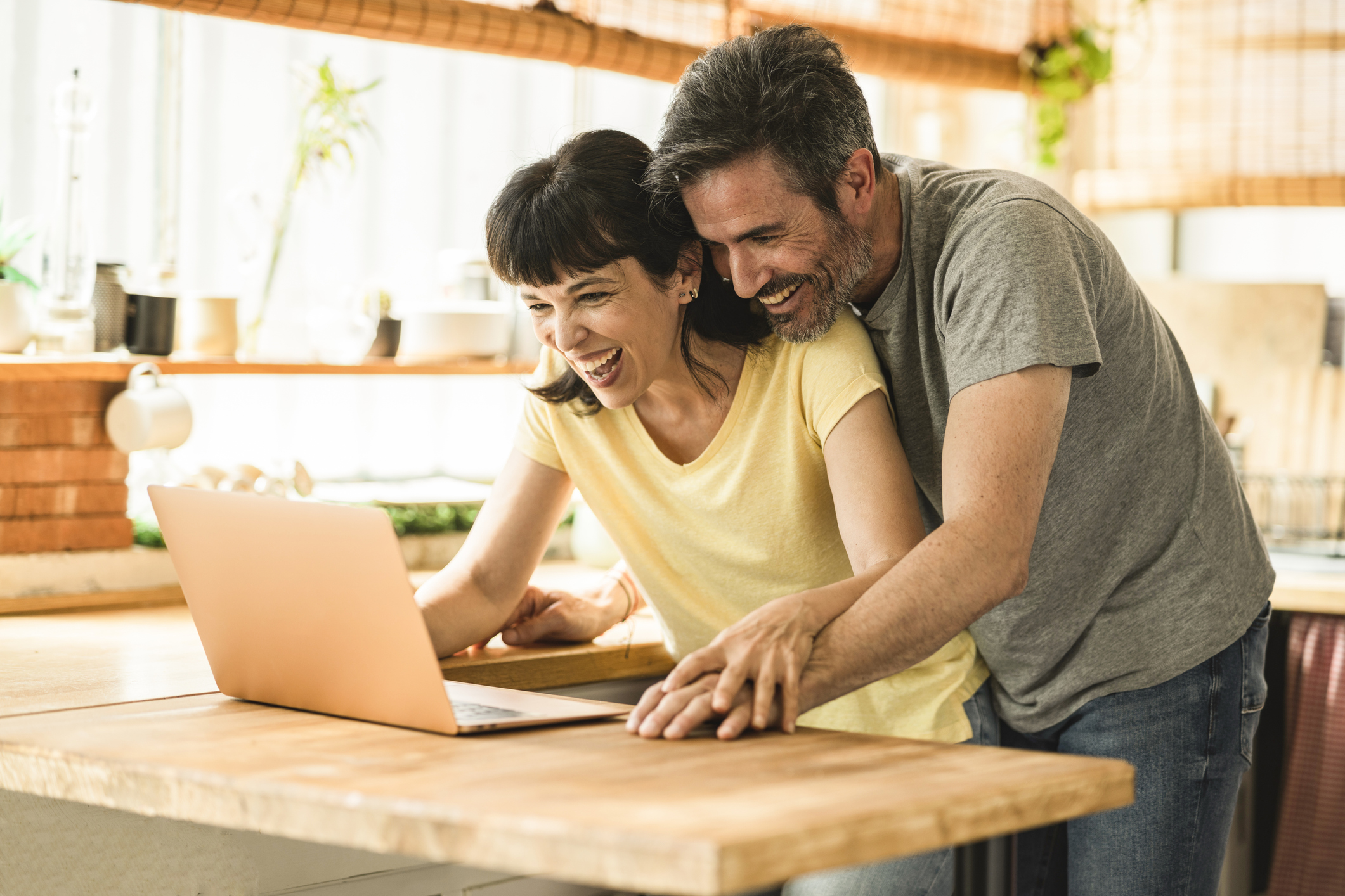 A man and woman smiling while looking at a laptop