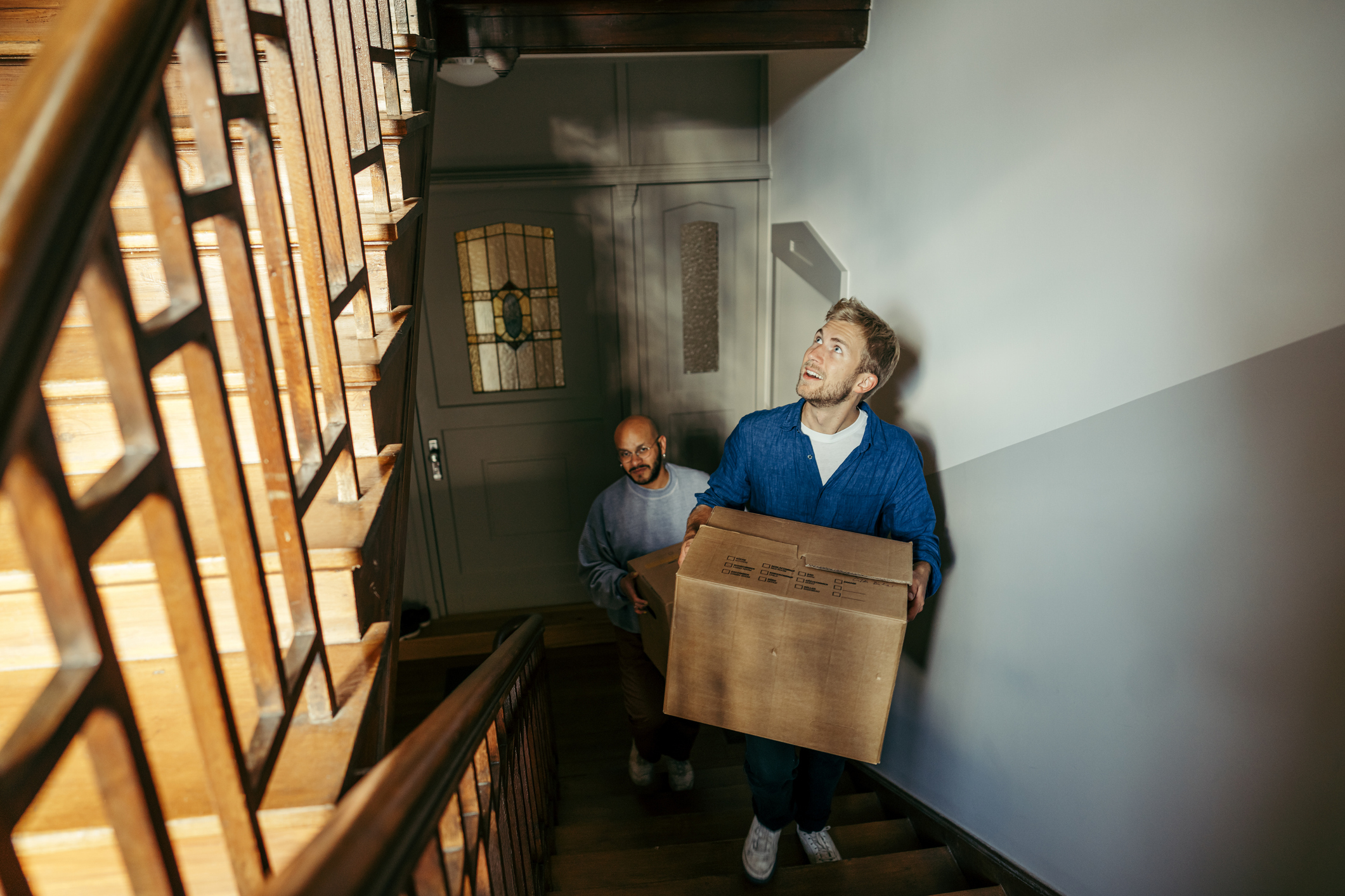 People carry boxes upstairs in a new home.