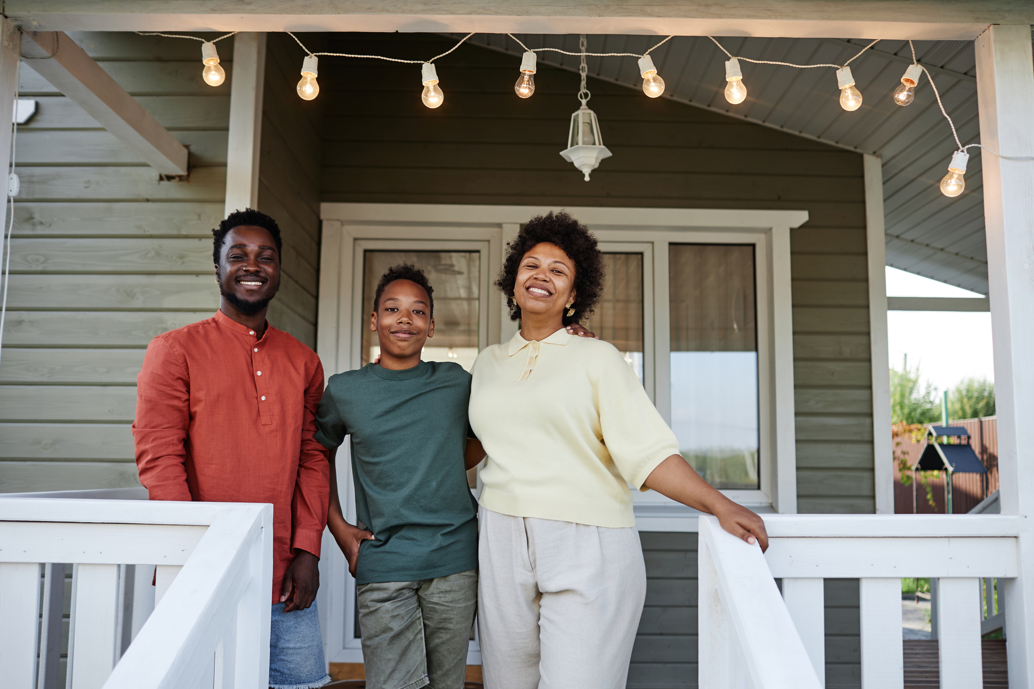 A family smiles on the porch of their new home.