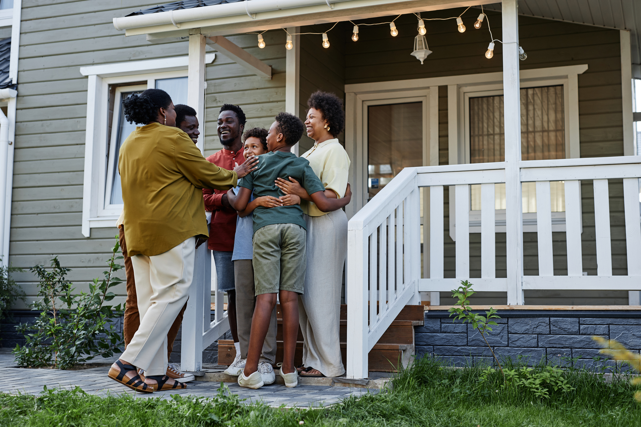 A group of people smiles while gathering outside of a house.
