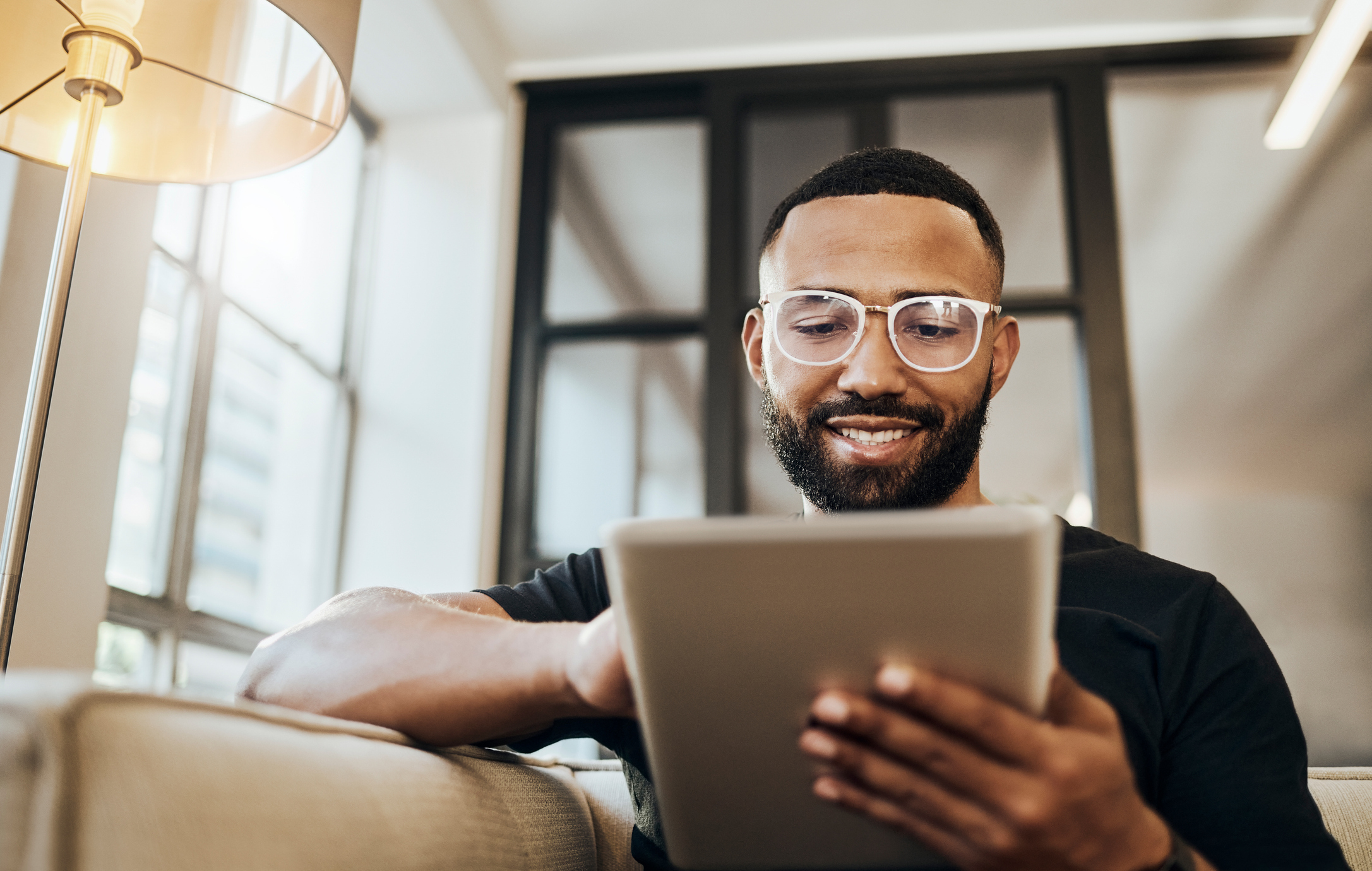 A man smiles at a tablet.