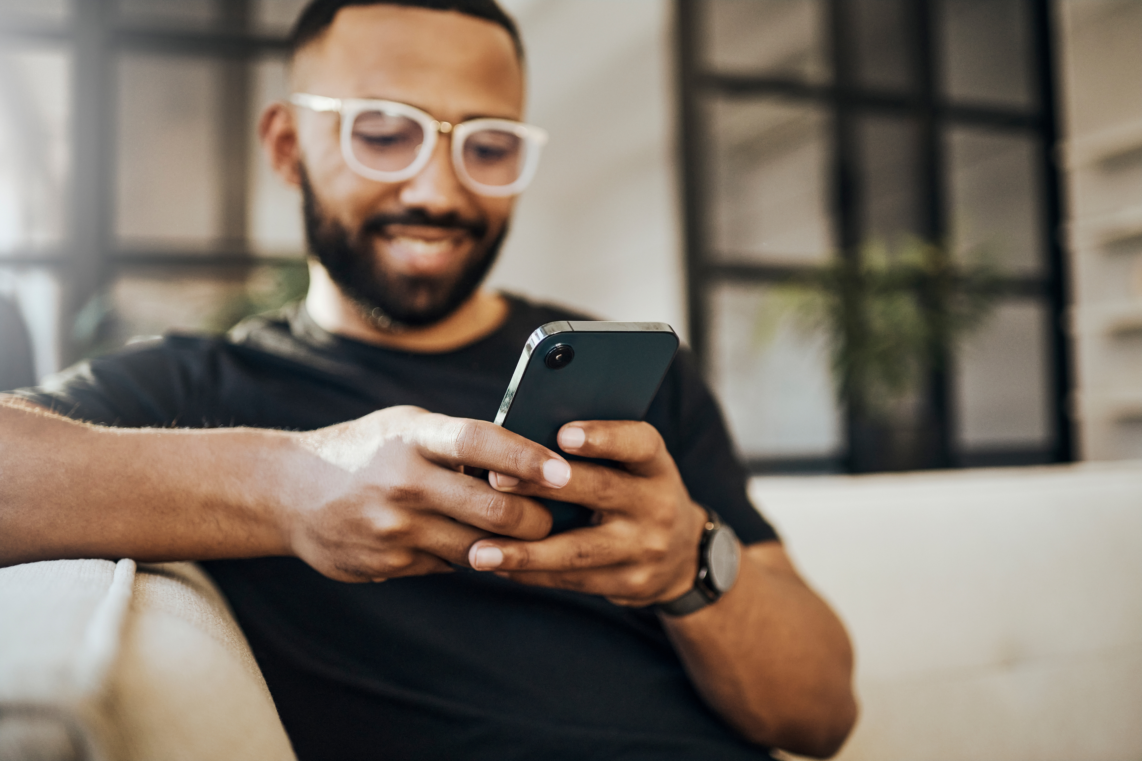 A man smiles while learning about credit score requirements for home equity loans on his phone.