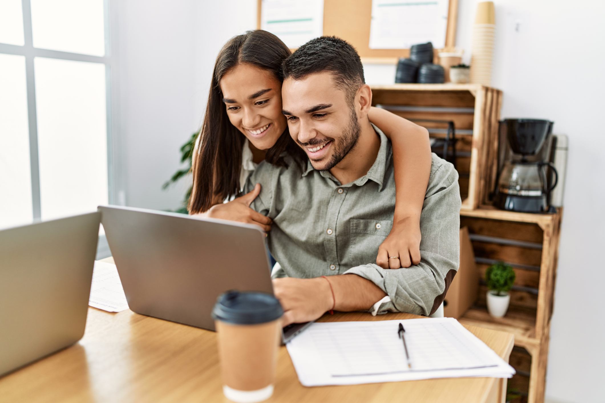 A man and a woman smiling at a laptop