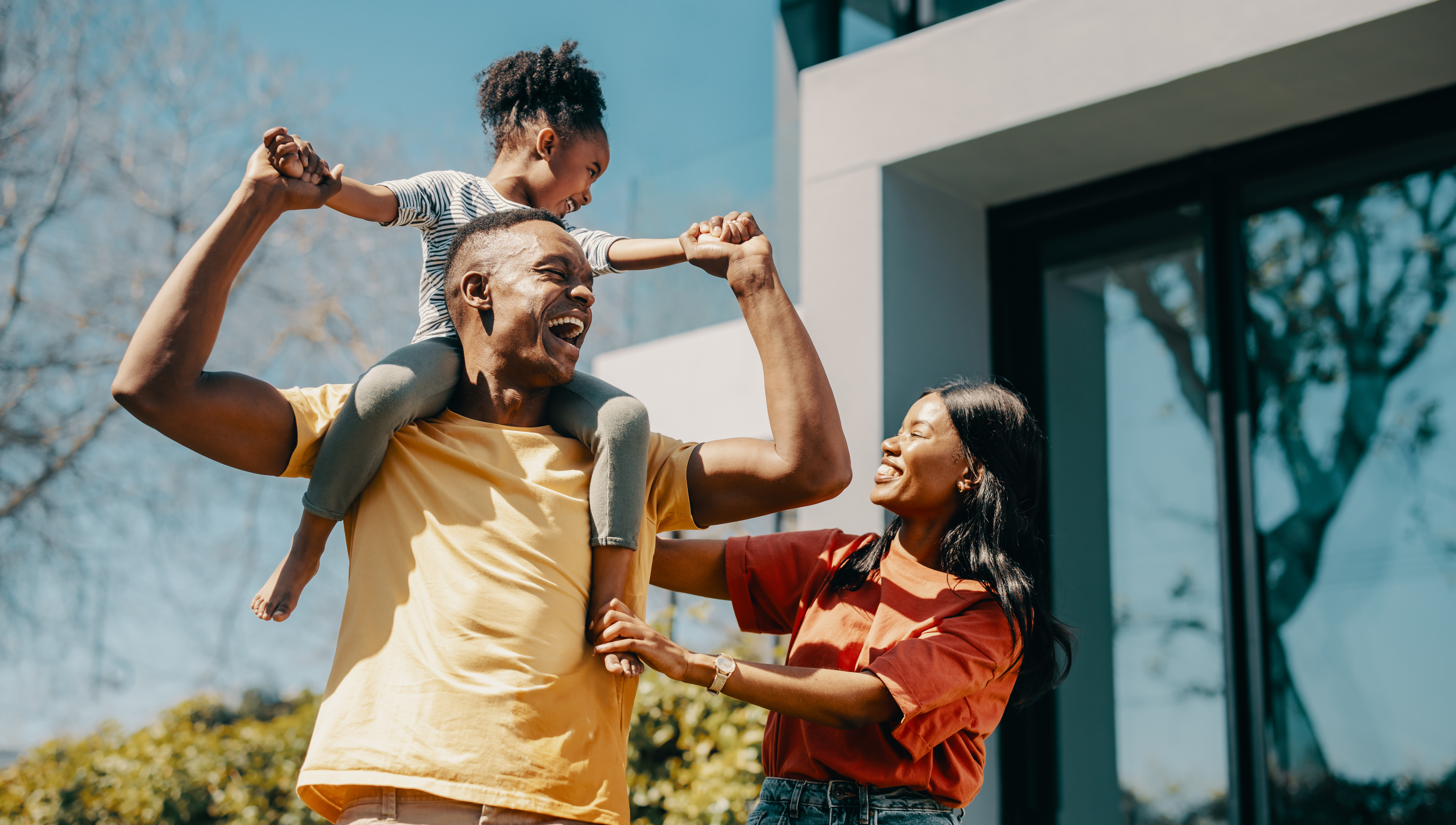 A family laughs outside of their new home.