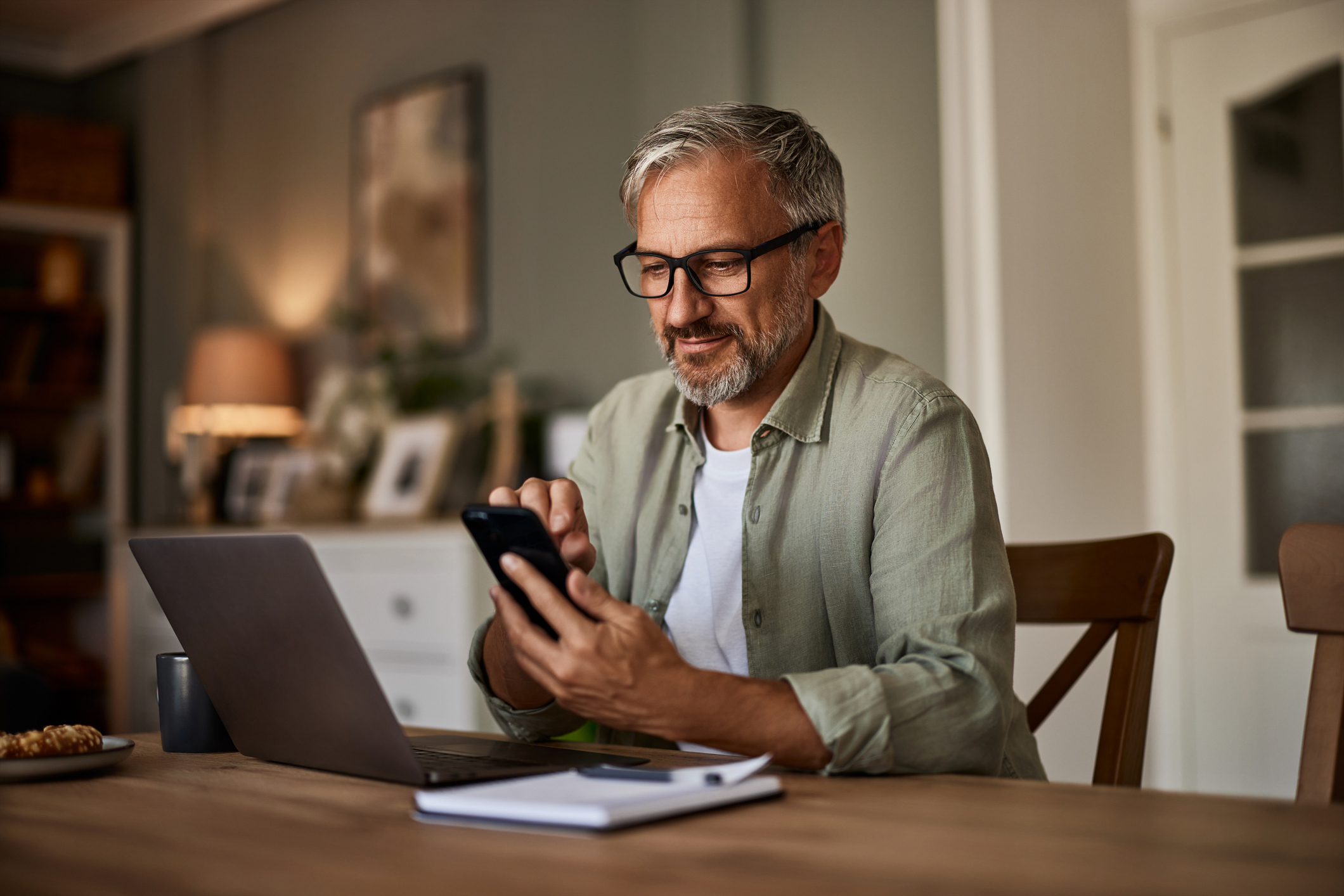 A man smiles at a phone while exploring loan options for a mortgage.