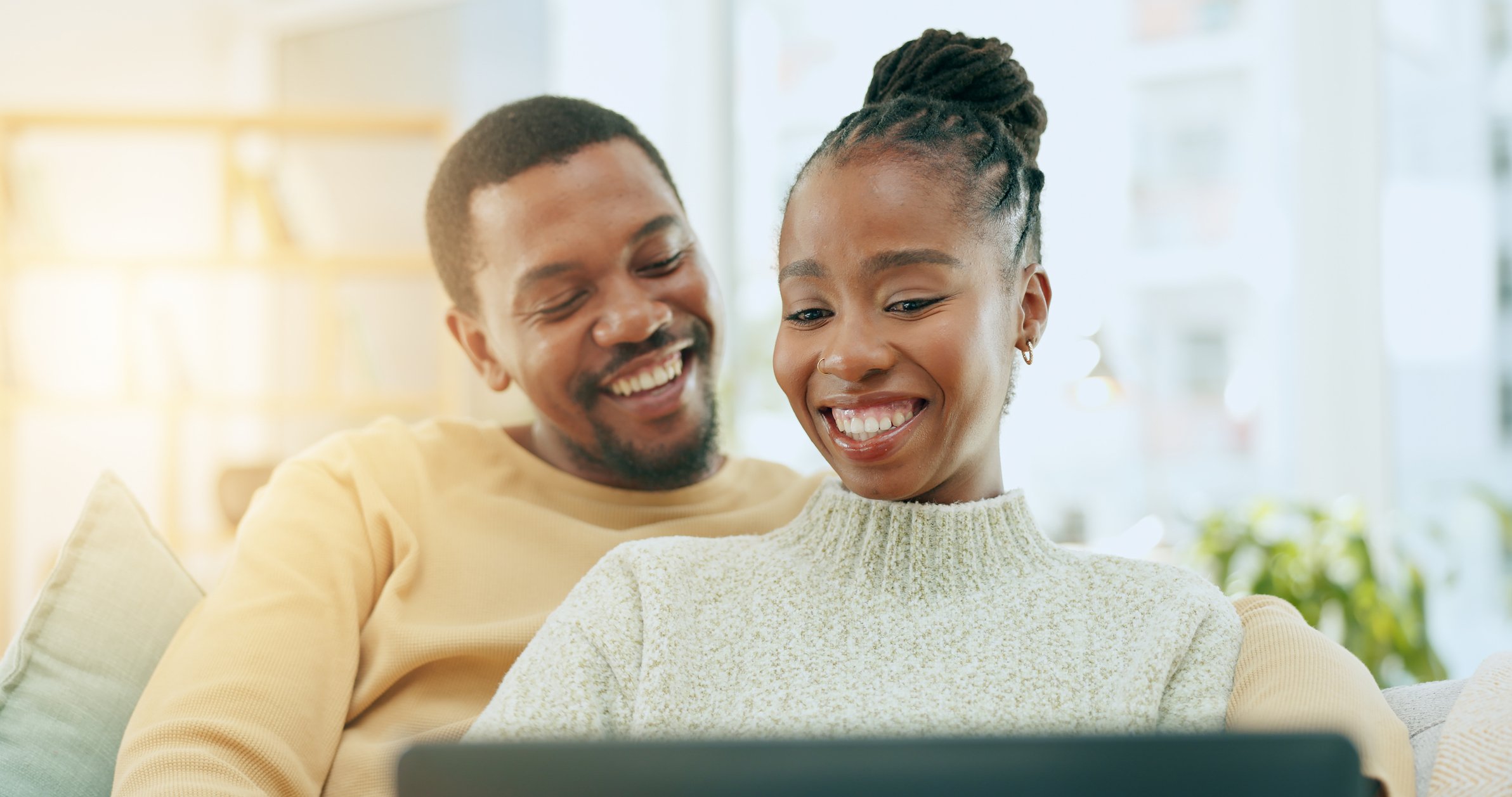 A man and a woman smiling at a laptop