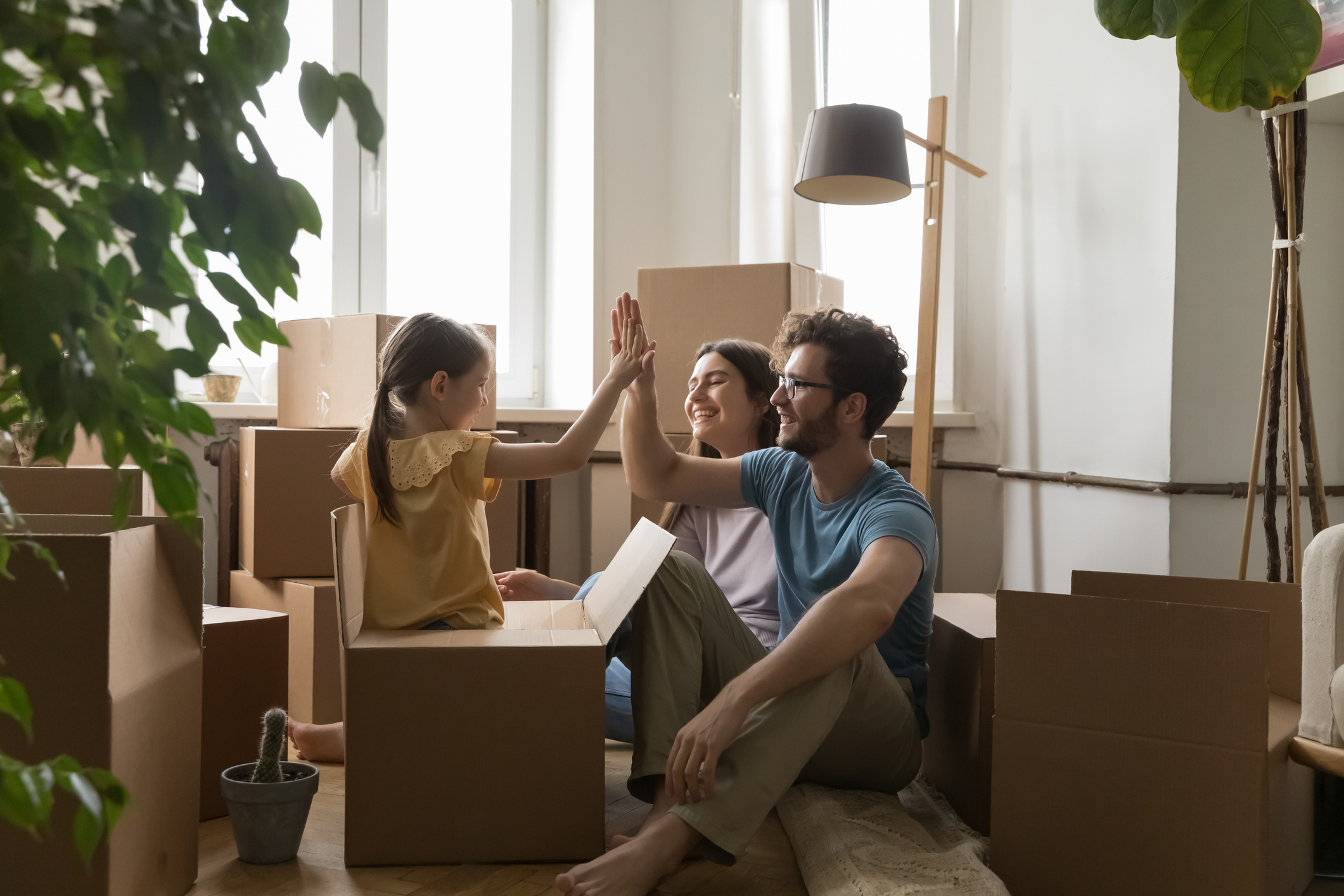 A man, woman, and child high-fiving while sitting on the floor surrounding by boxes