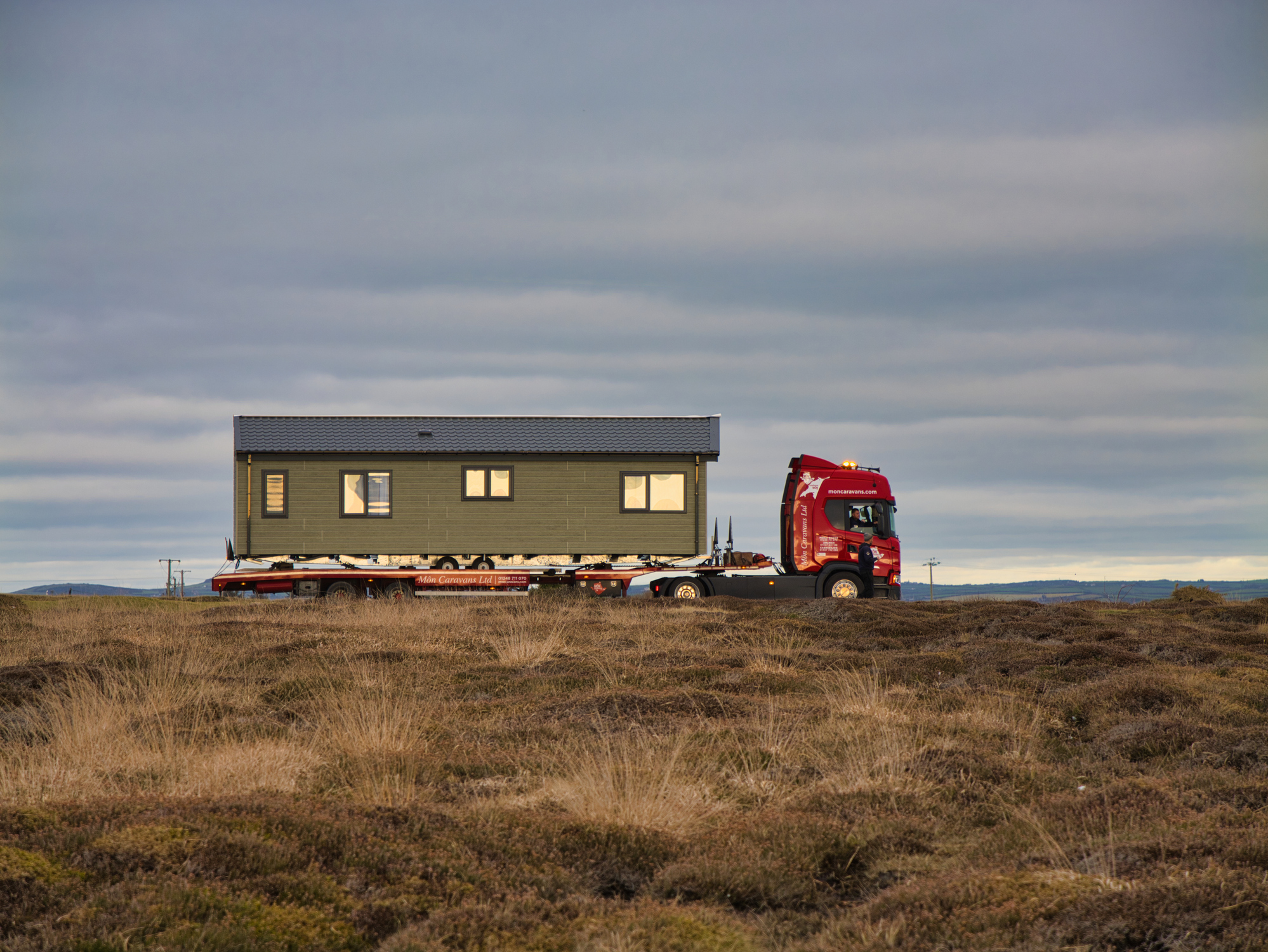 A small manufactured home is transported by truck.