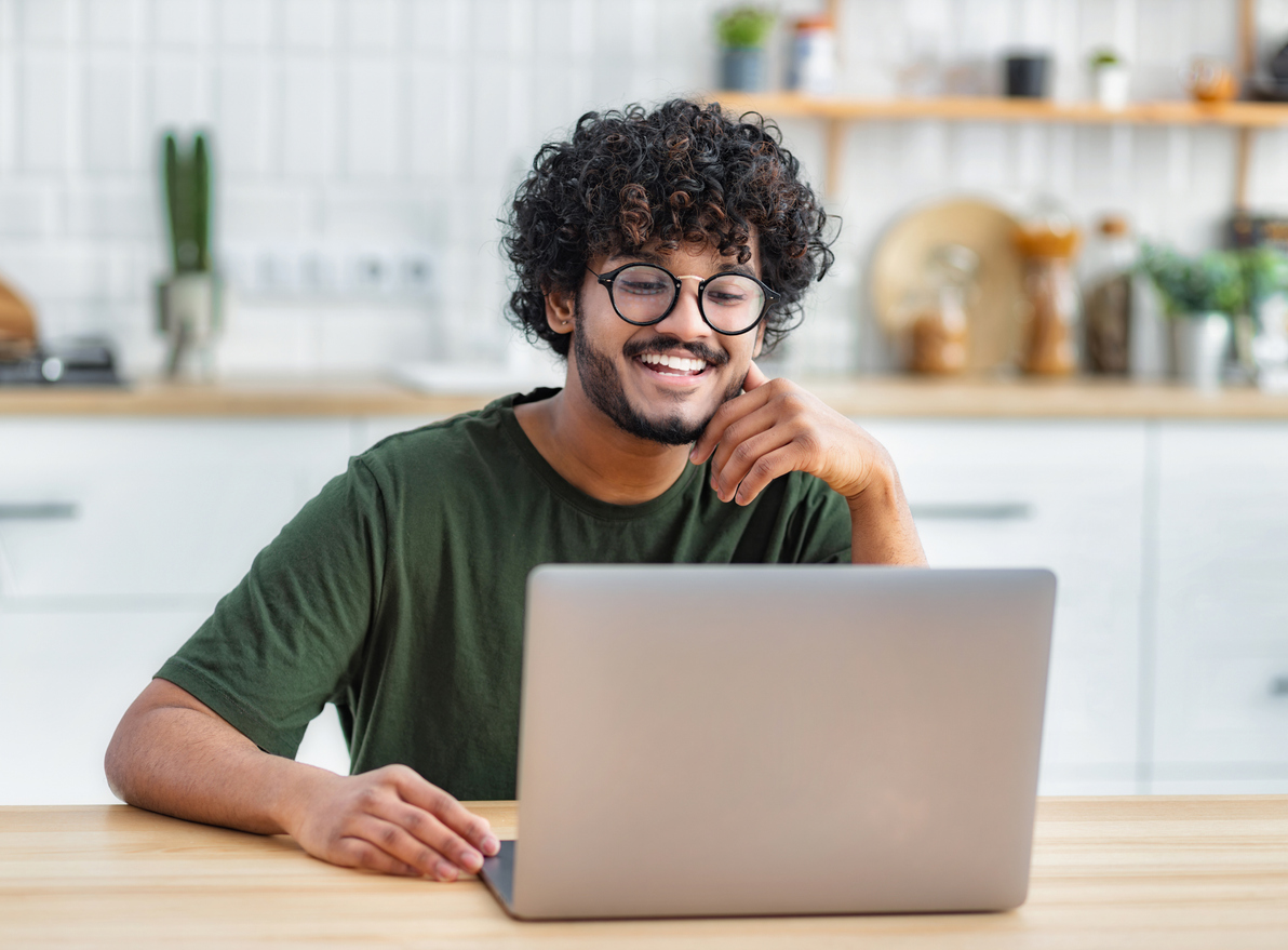 A man smiles while using a laptop.