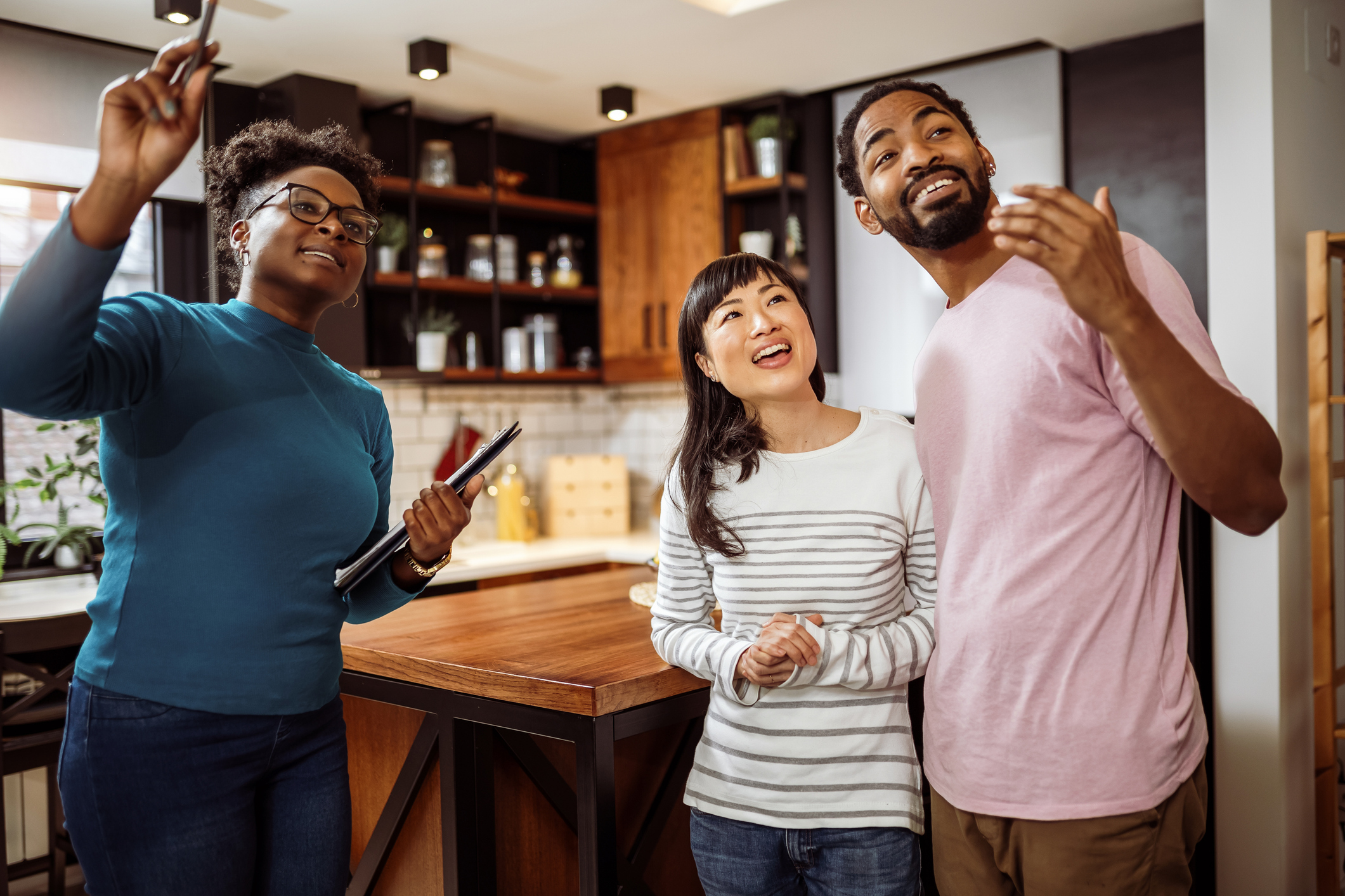 A real estate agent giving a man and woman a tour of a house.