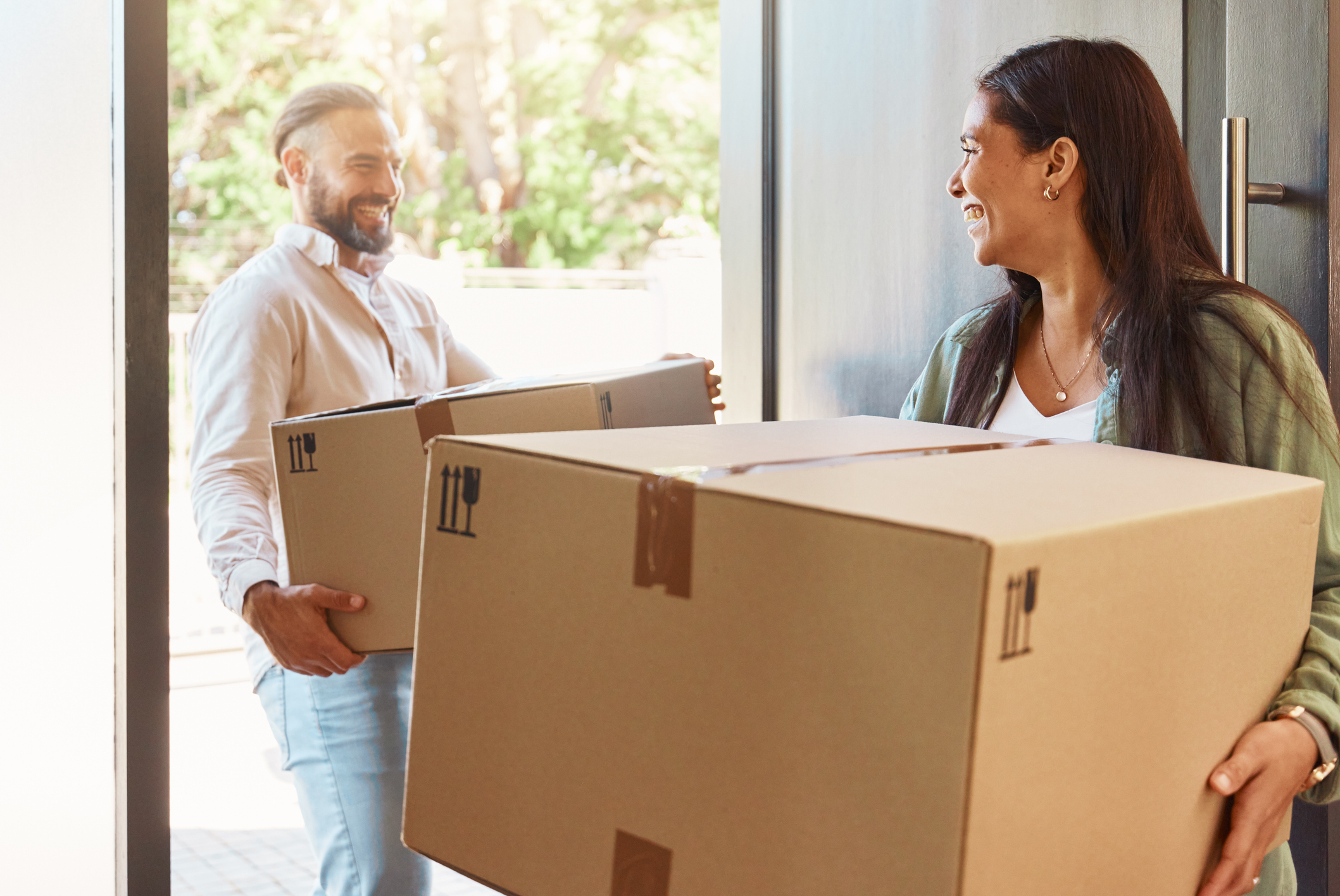 A man and a woman move a box into a house.