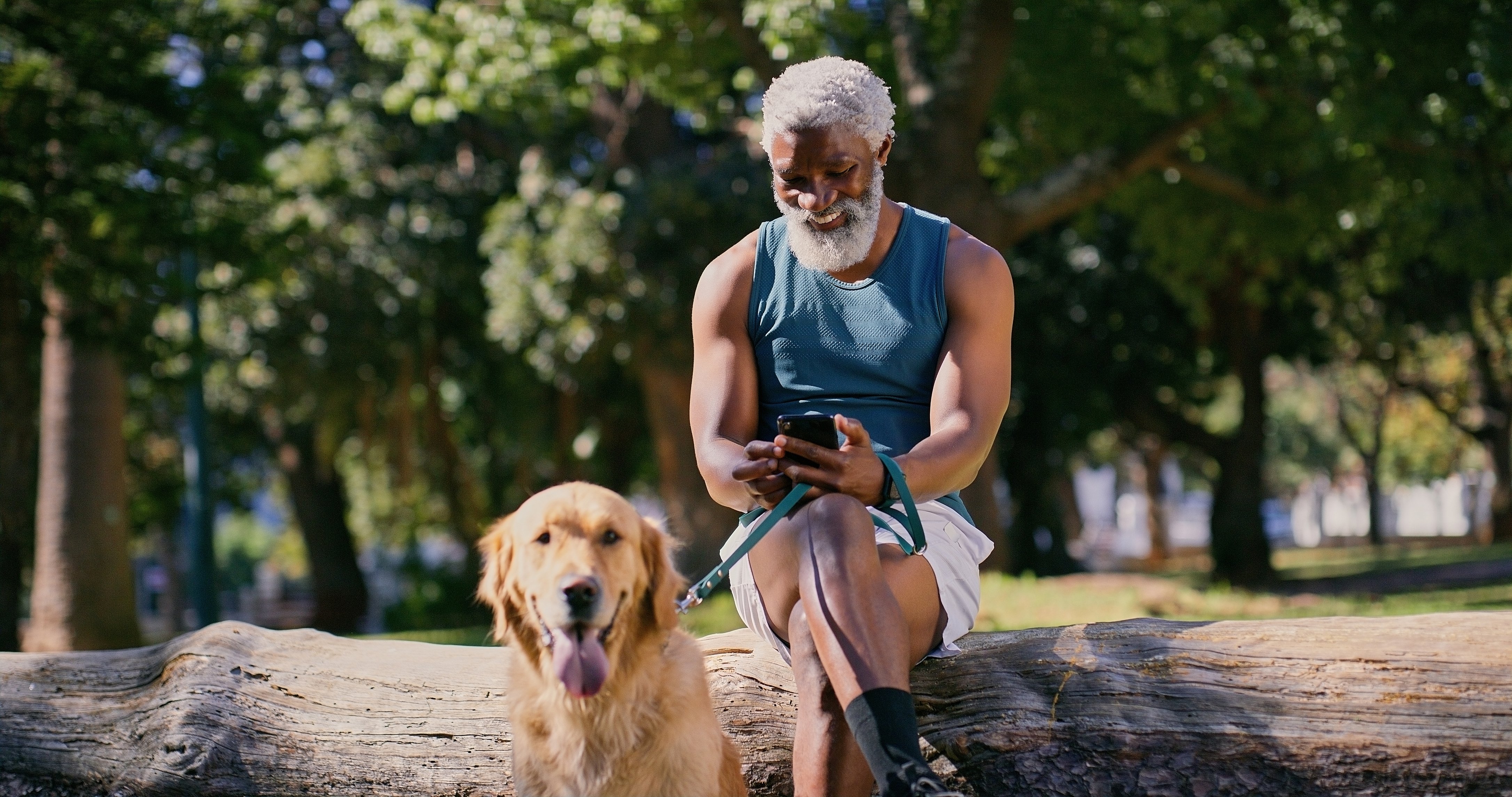 A man smiles while holding his golden retriever on a leash.