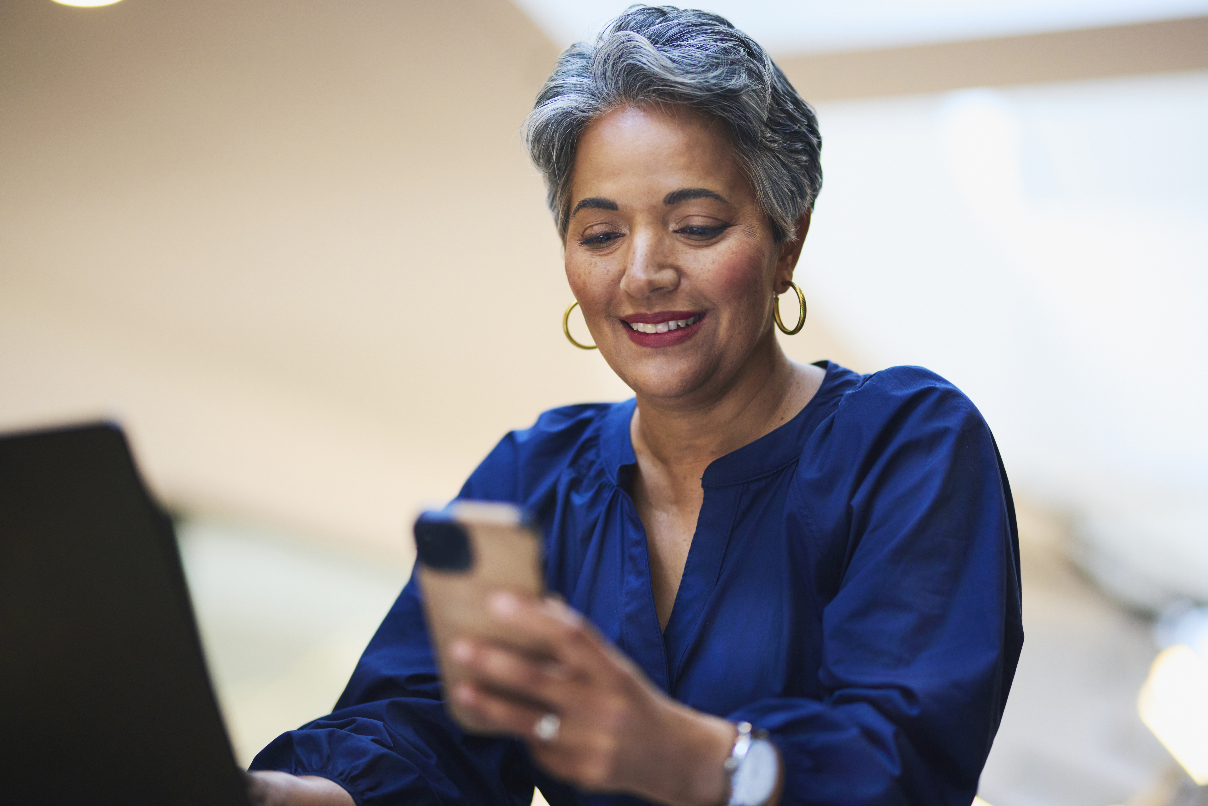 An older woman smiles at her phone.