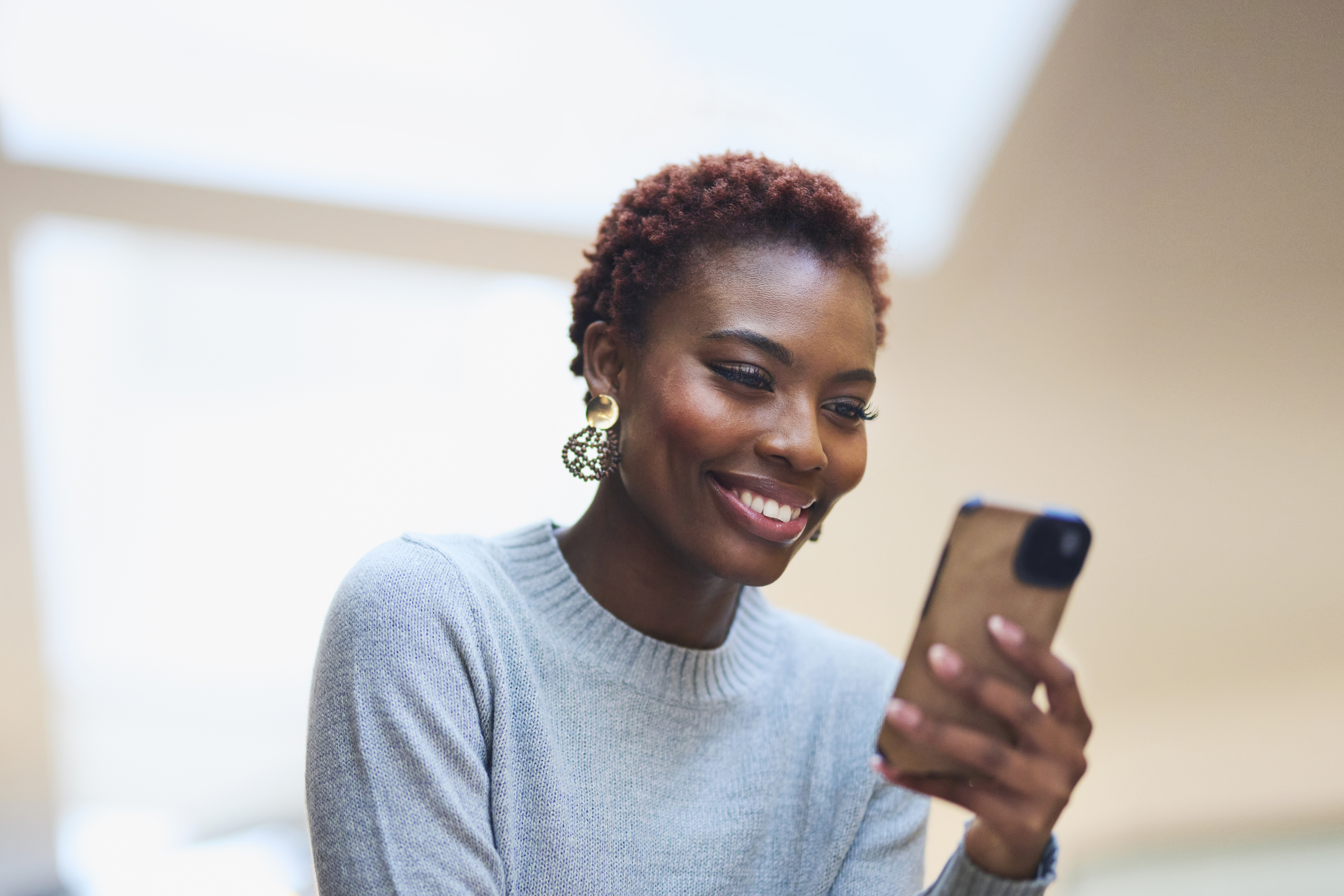 A woman smiles at her phone.