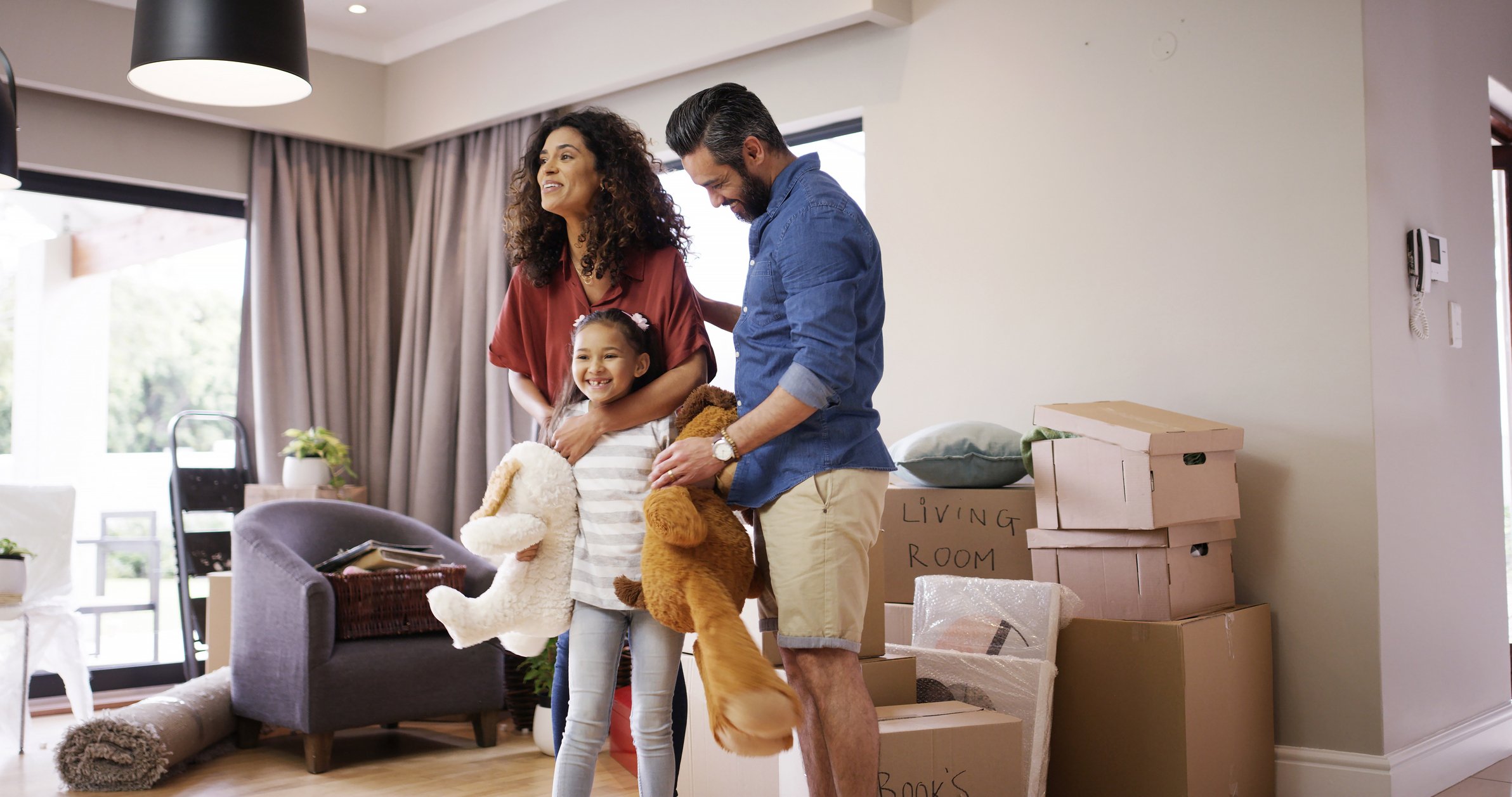 A man, woman, and child smile while moving into a new house.