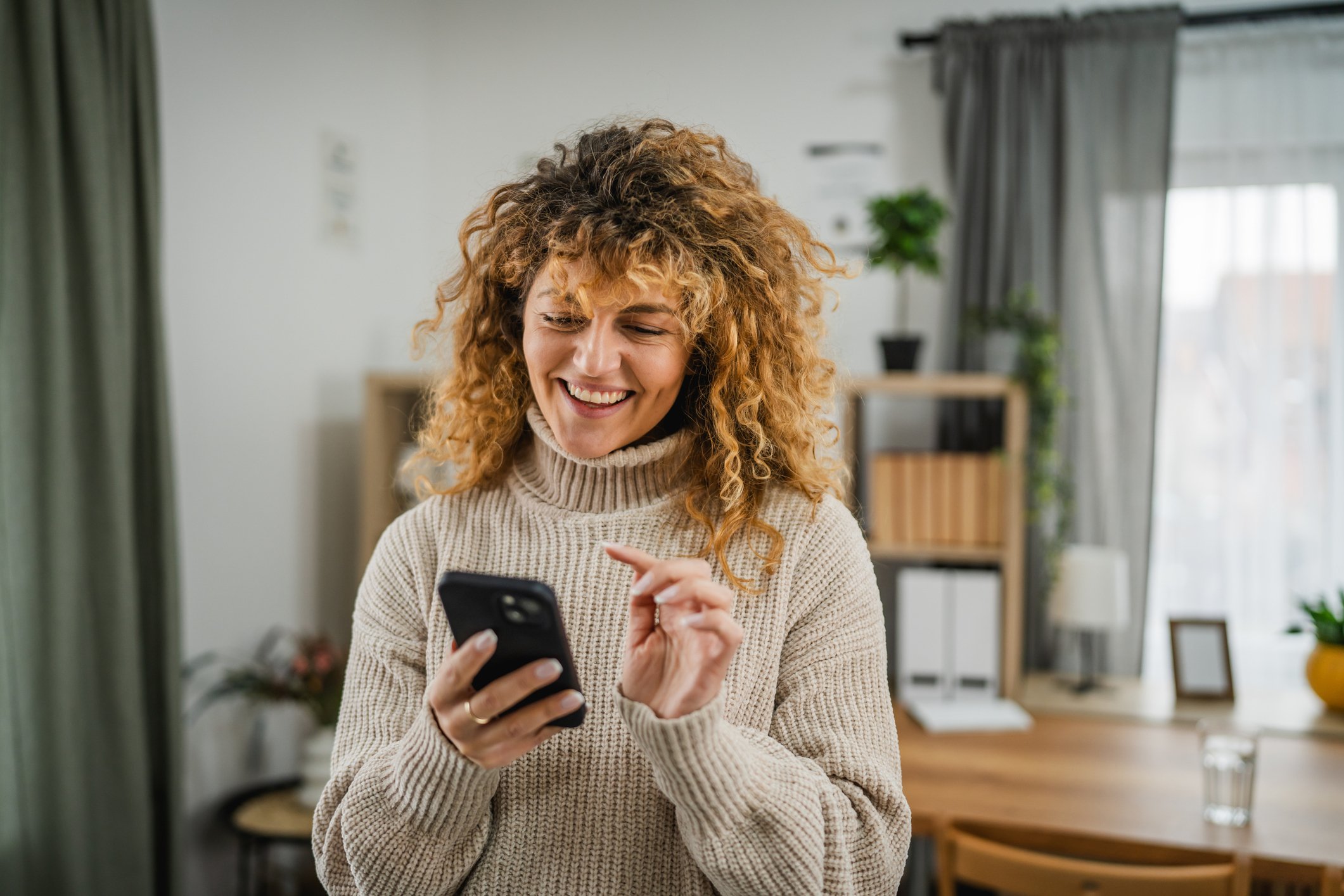 A woman smiles while calculating her break-even timing on a refinance.