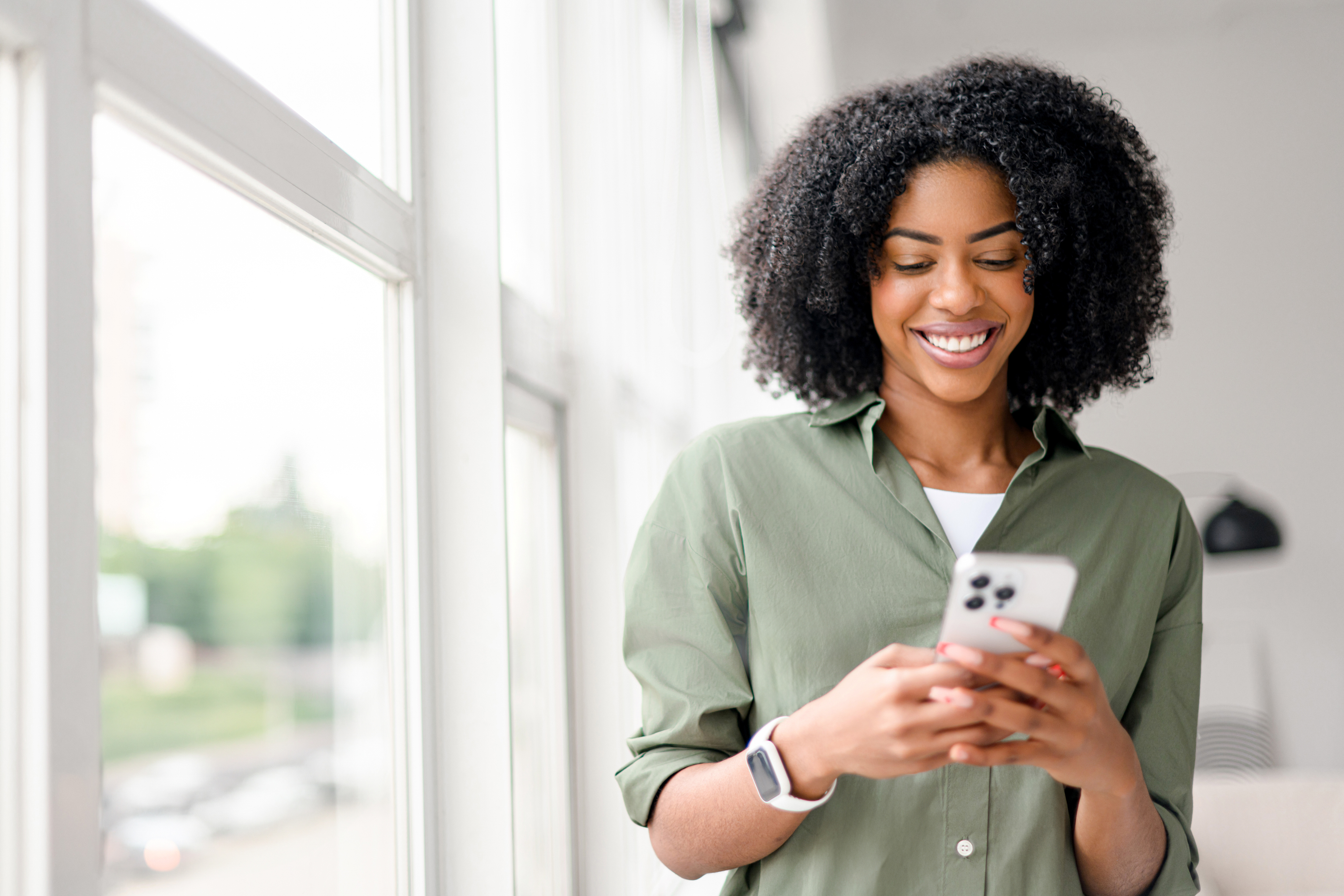 A woman smiles at a phone while estimating jumbo loan closing costs.