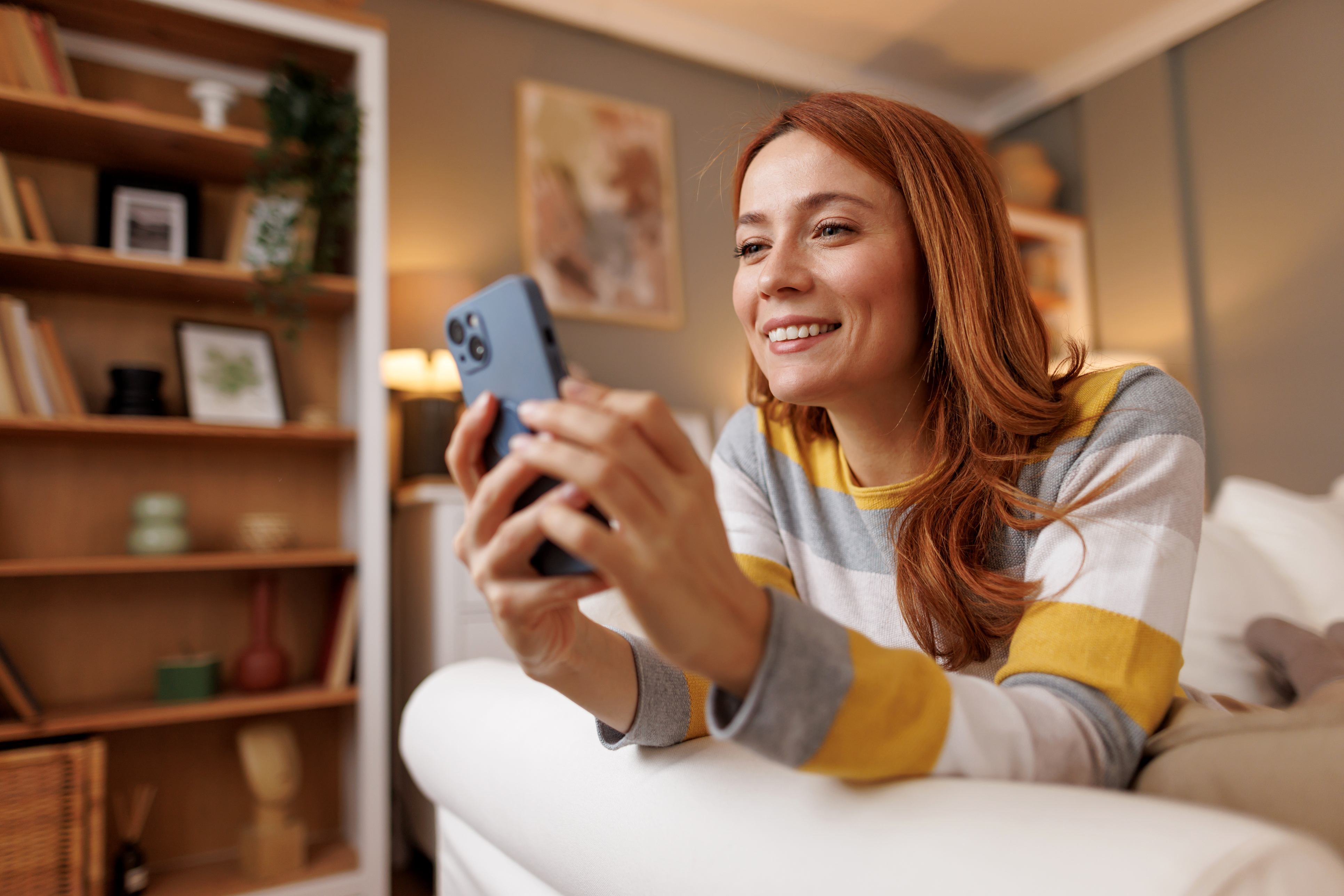 A woman smiles while looking through cash-out refinance options on her phone.