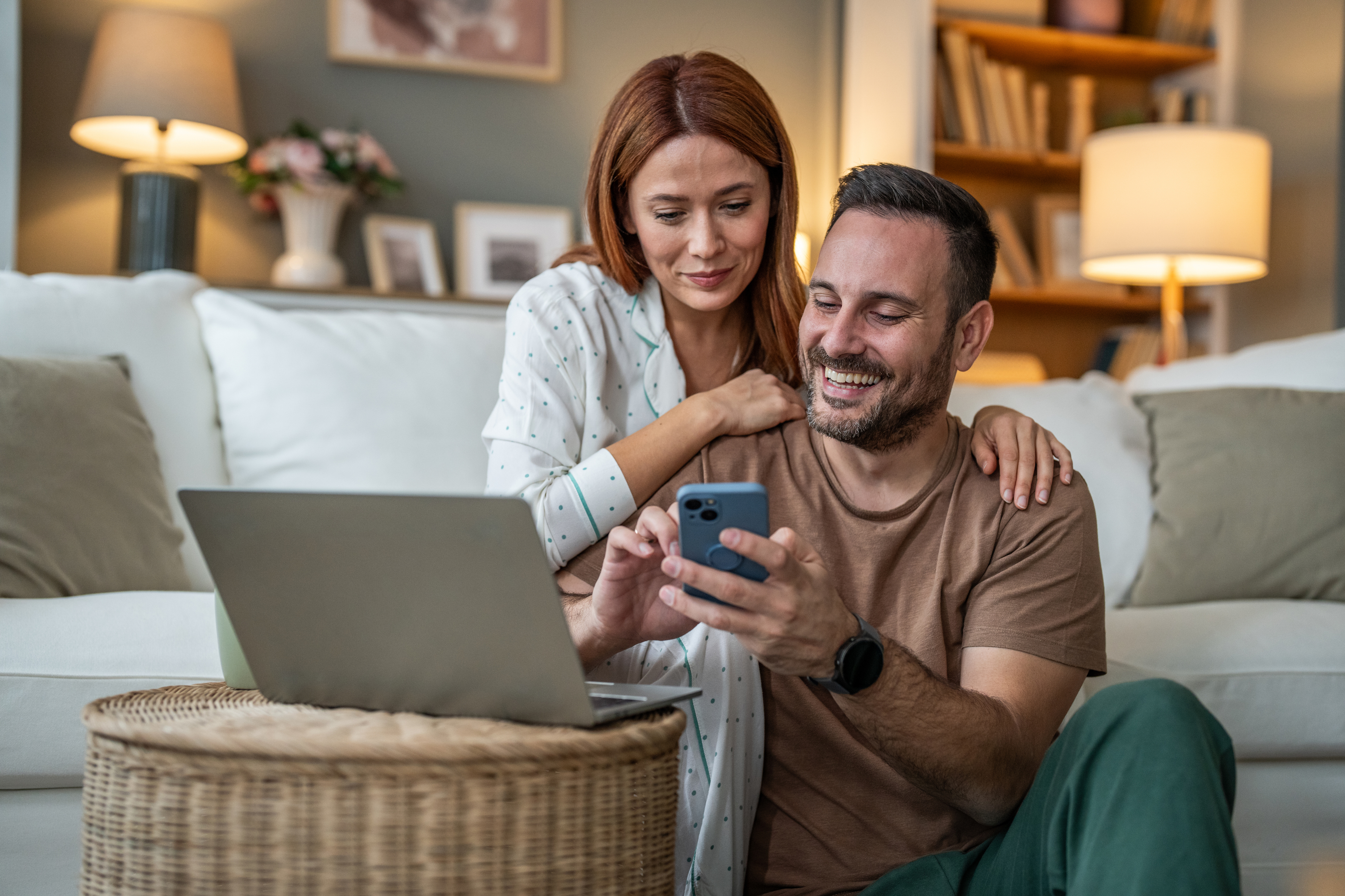 A couple smiles at a phone while exploring second home loan options.