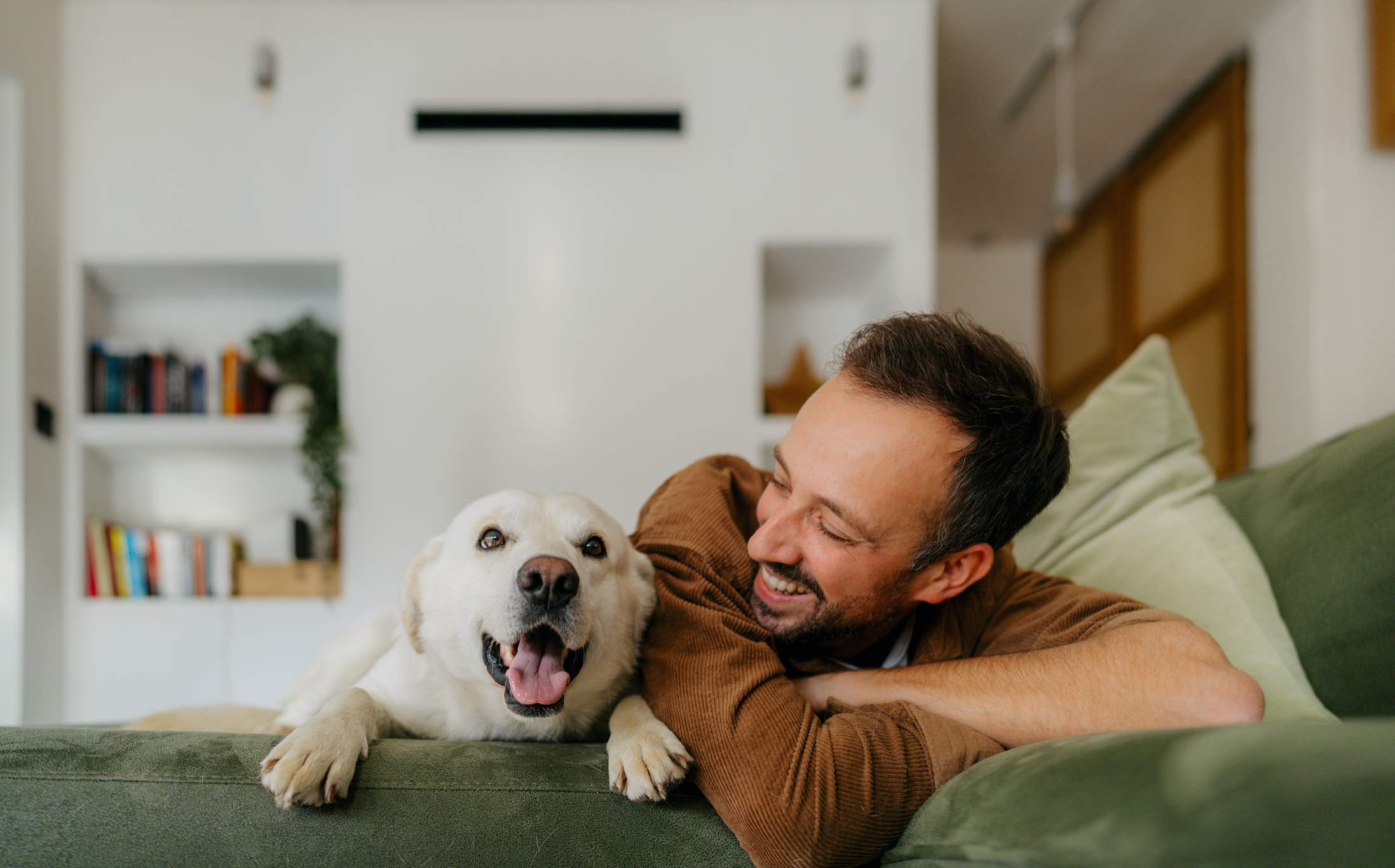 A man and a yellow lab smile while hanging out in their home.