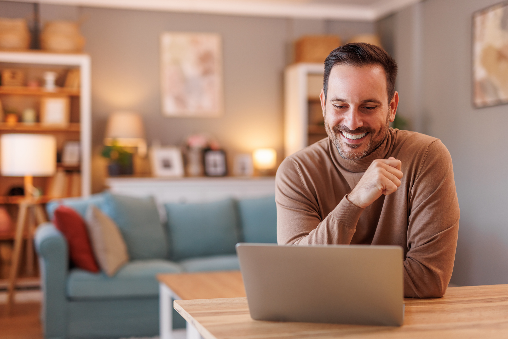 A man smiles at a laptop.