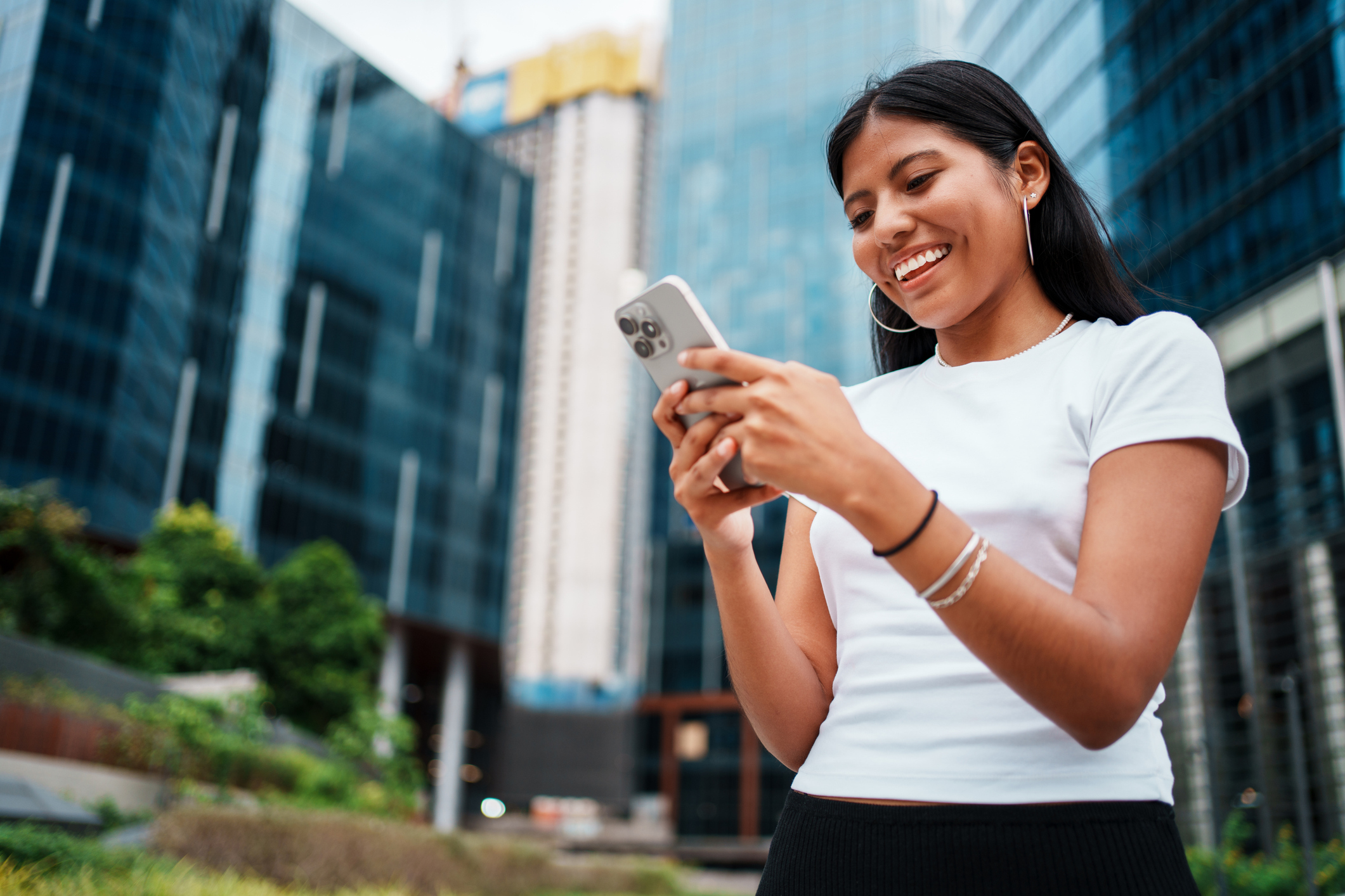 A woman smiles while looking at her phone.