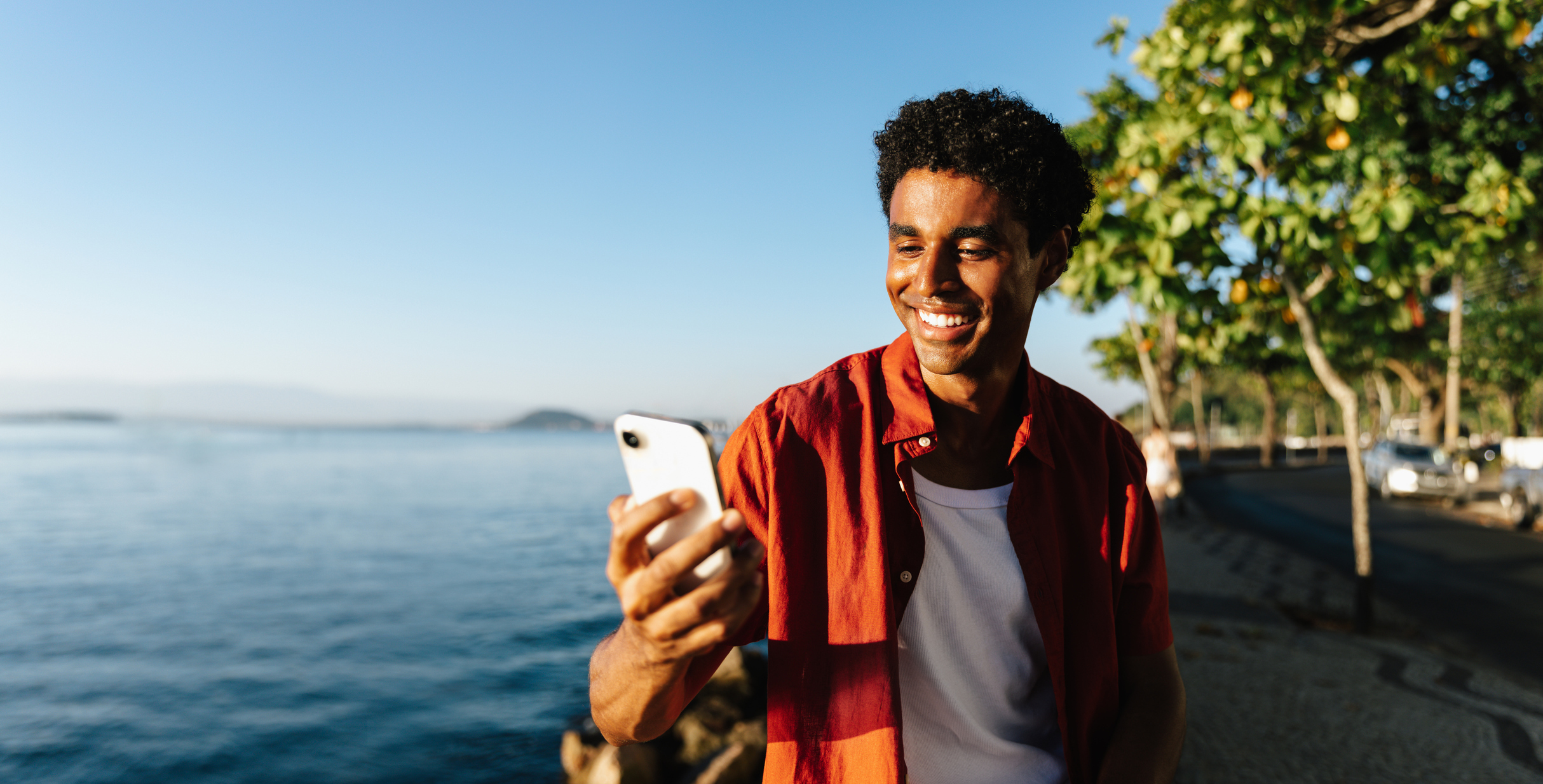 A man smiles at a phone while estimating his VA funding fee amount.